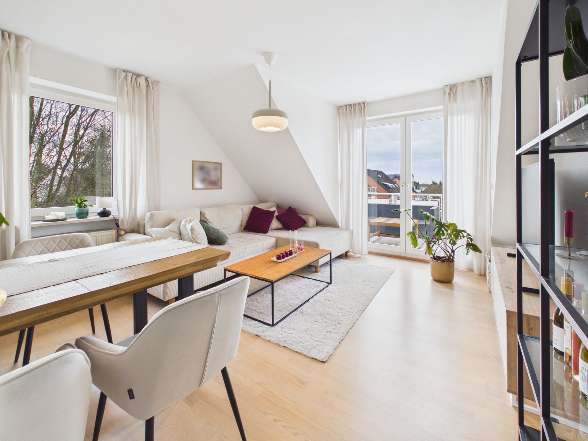 Helles Wohnzimmer mit Ecksofa, Esstisch, Teppich und großen Fenstern zur Terrasse.