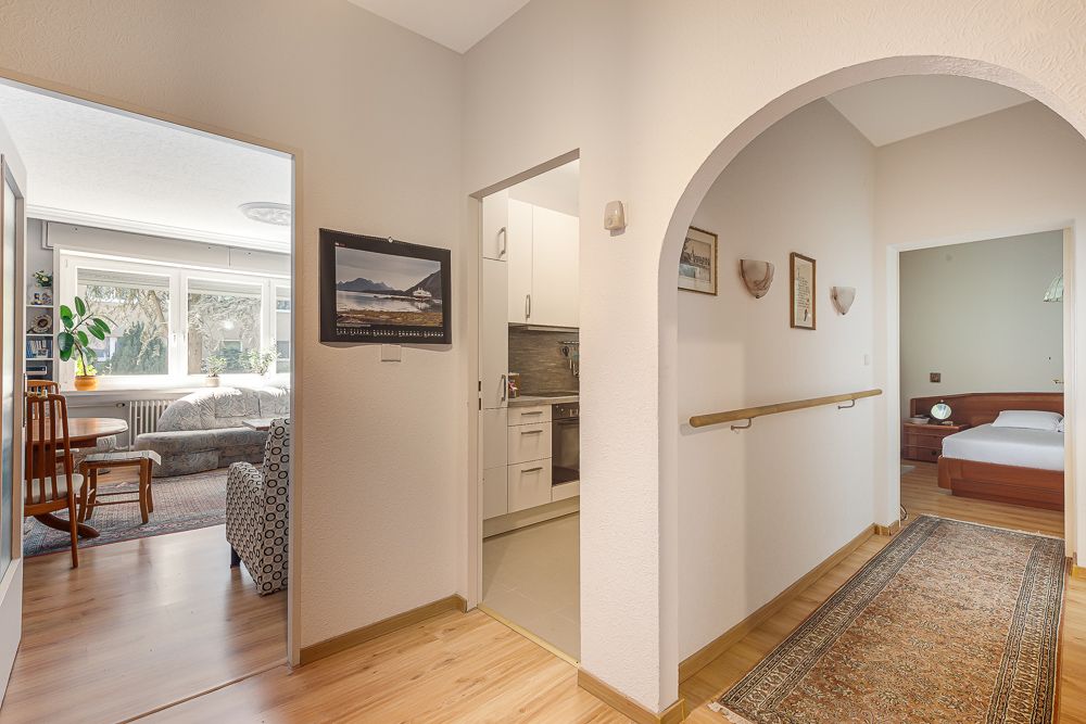 Heller Flur mit Blick in Wohnzimmer, Küche und Schlafzimmer, Holzboden und Teppichläufer.