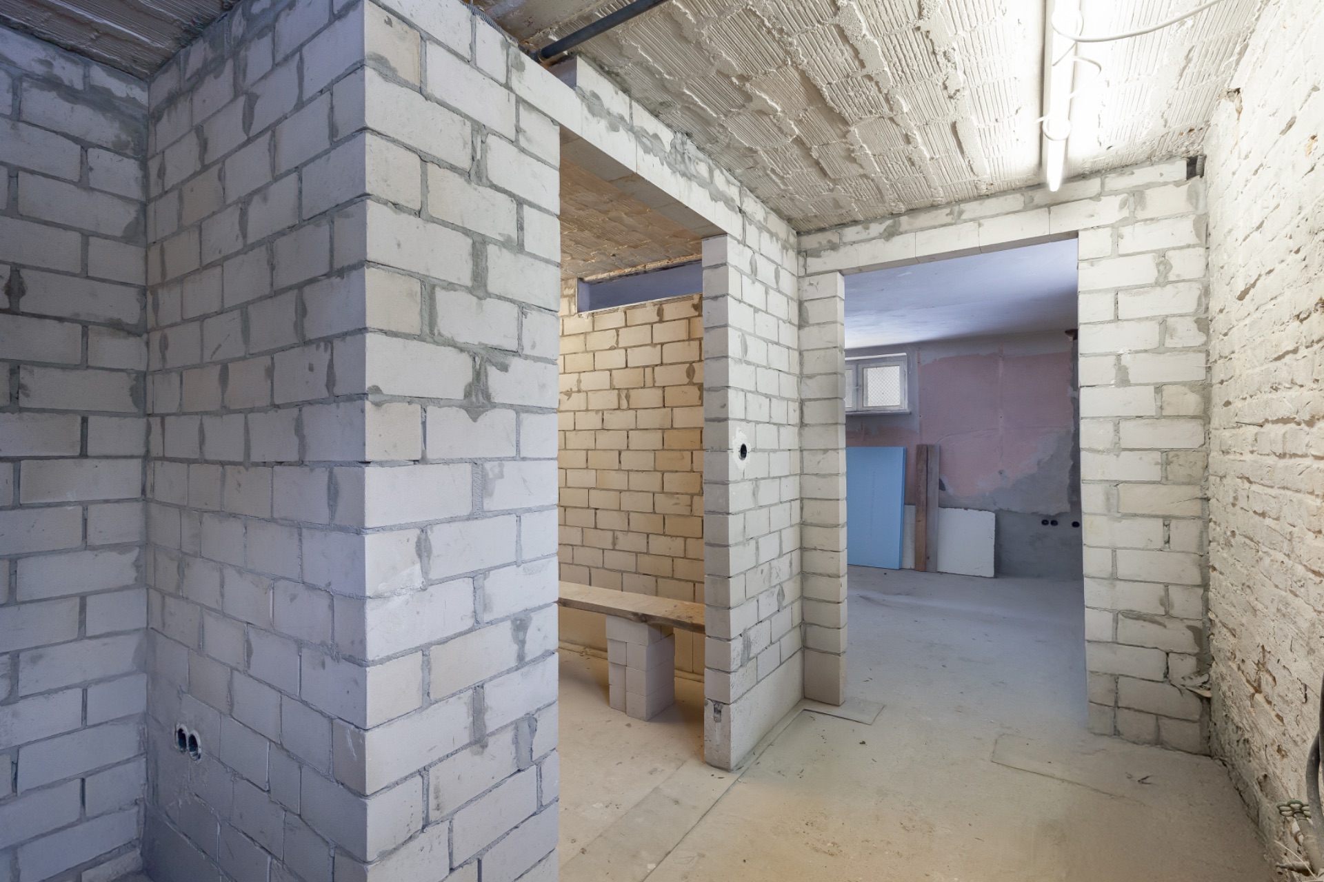 Innenraum eines Hauses im Rohbau mit unverputzten Wänden und offenen Türöffnungen.