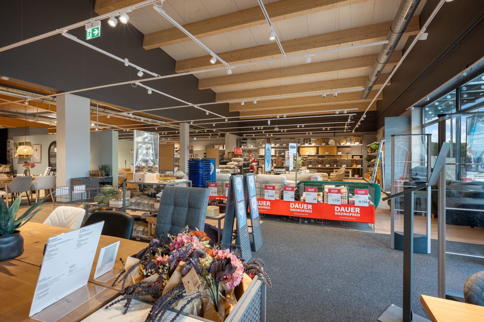 Innenraum eines Möbelgeschäfts mit Ausstellung von Möbeln, Dekorationen und großen Fenstern.