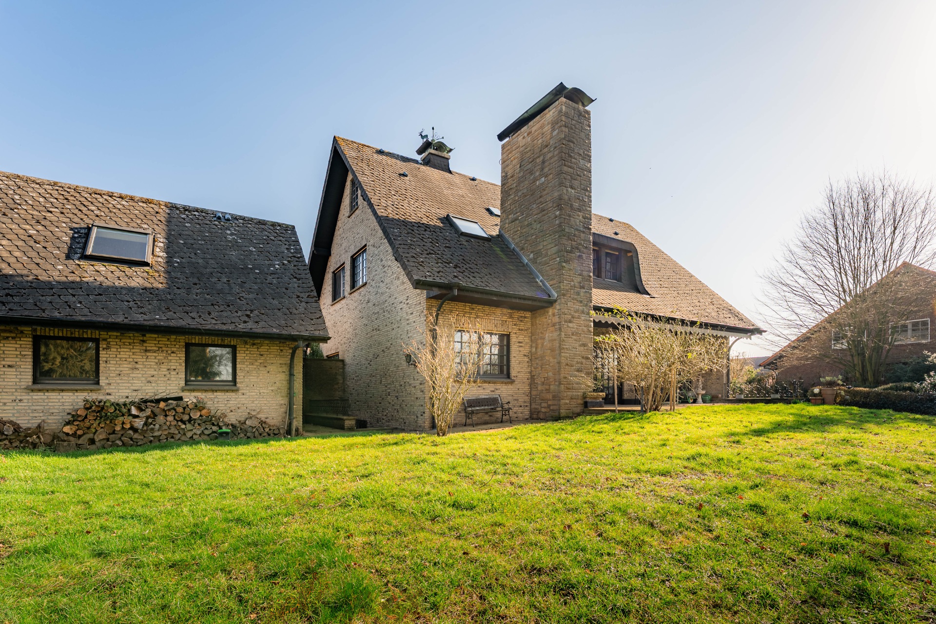 Zweistöckiges Haus aus Stein mit Schornstein und großem Garten im Vordergrund.