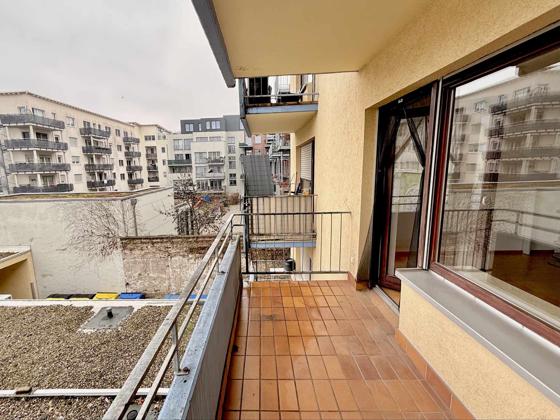 Blick von einem Balkon auf einen Innenhof mit mehreren Wohngebäuden.