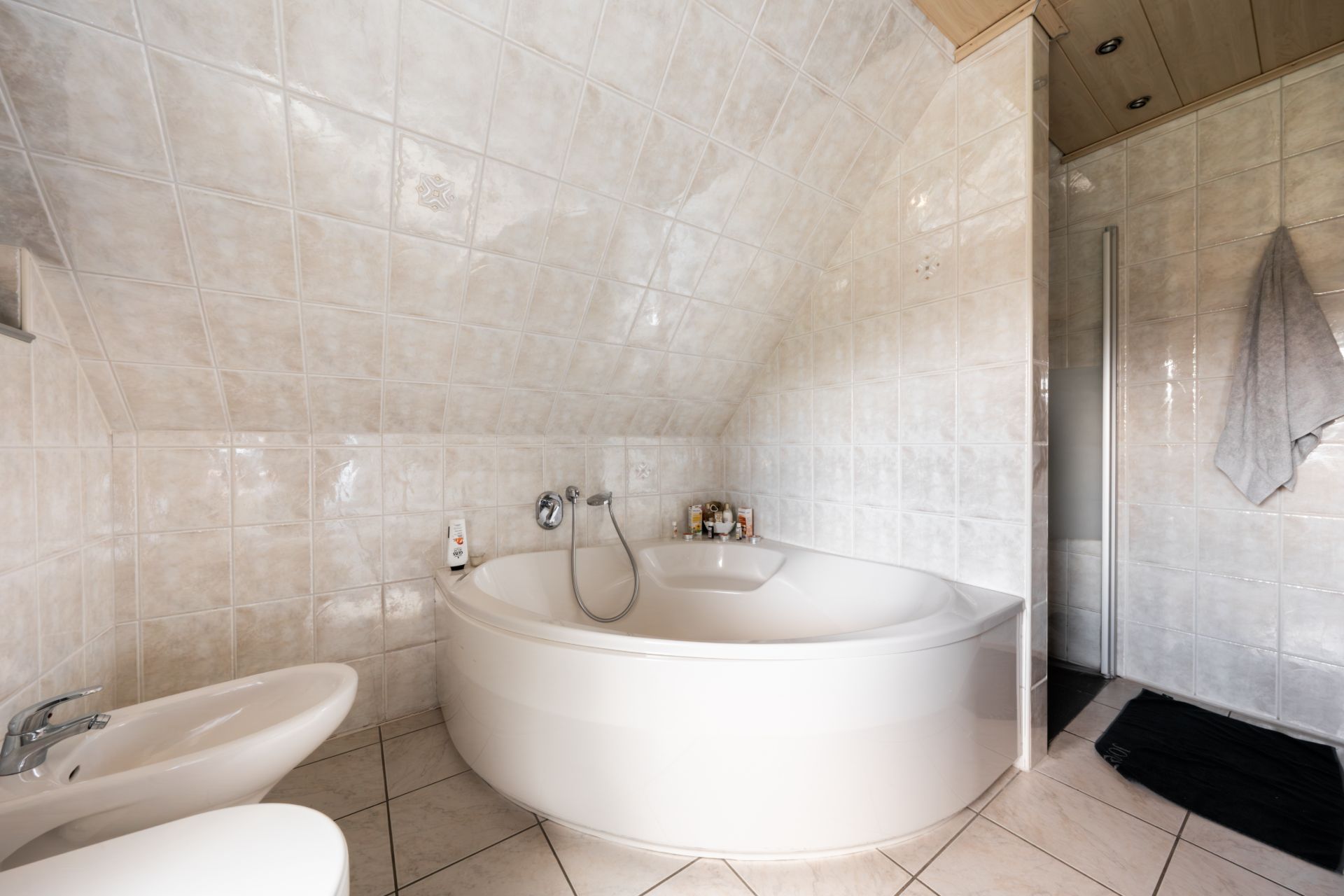Badezimmer mit Eckbadewanne, Bidet und Handtuch an der Wand.
