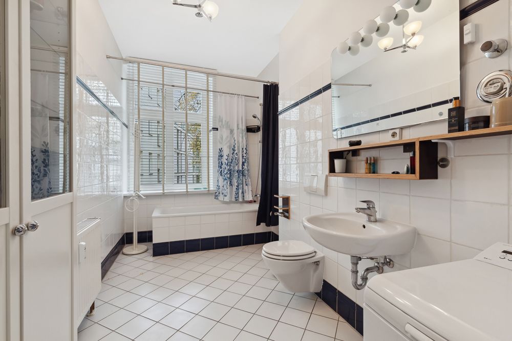 Modernes Badezimmer mit Badewanne, Waschbecken, Spiegel, WC und großem Fenster.