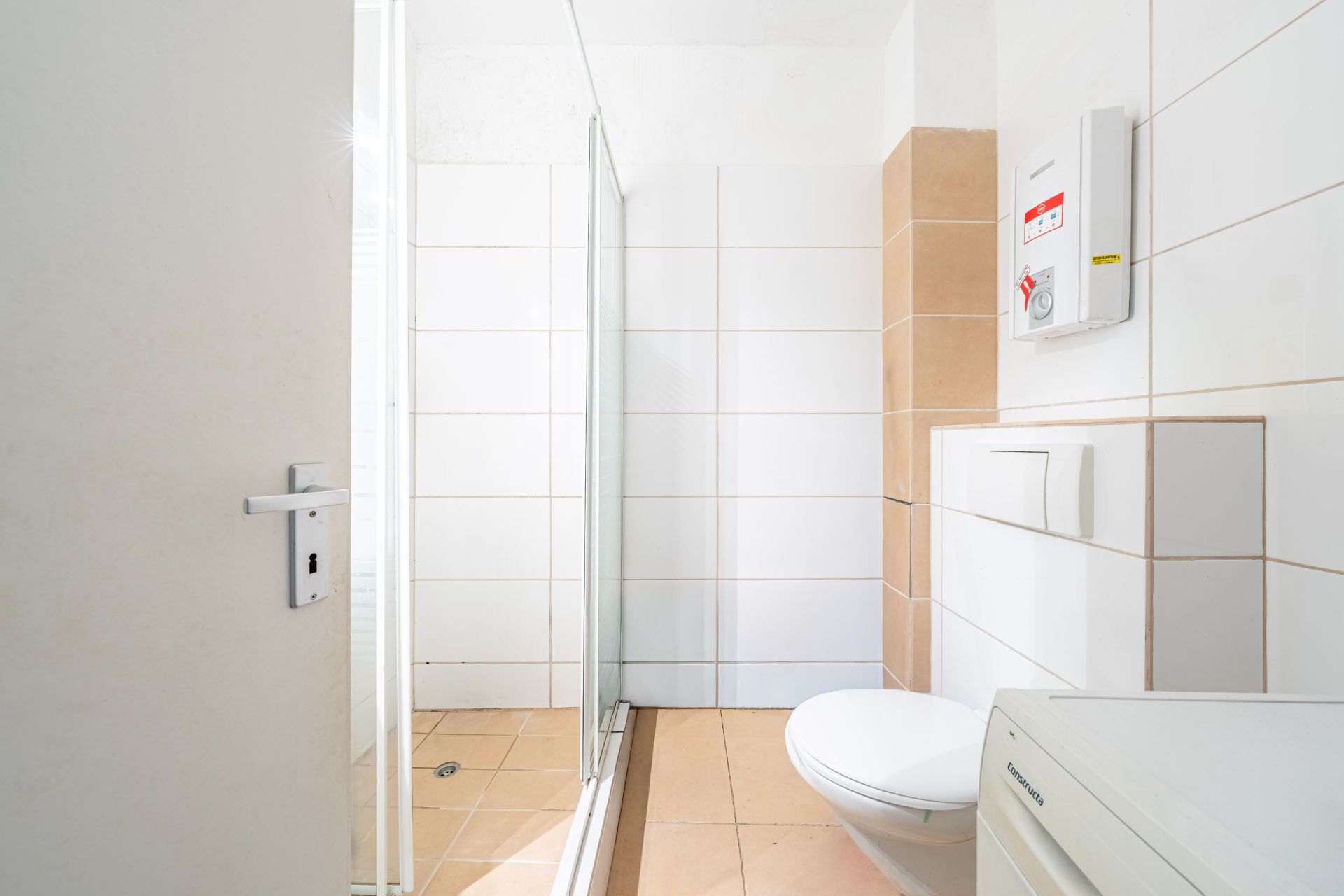 Modernes Badezimmer mit Dusche, WC und weißen Fliesen.