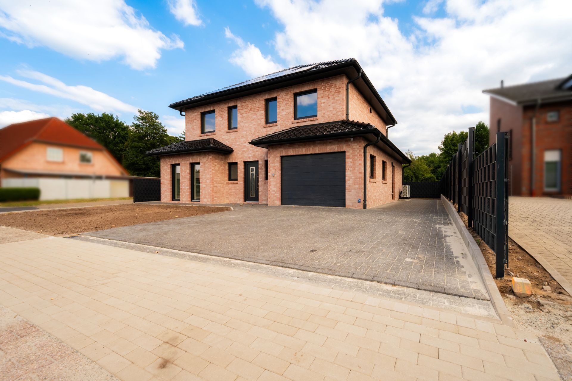 Modernes zweistöckiges Backsteinhaus mit Garage und gepflasterter Einfahrt.