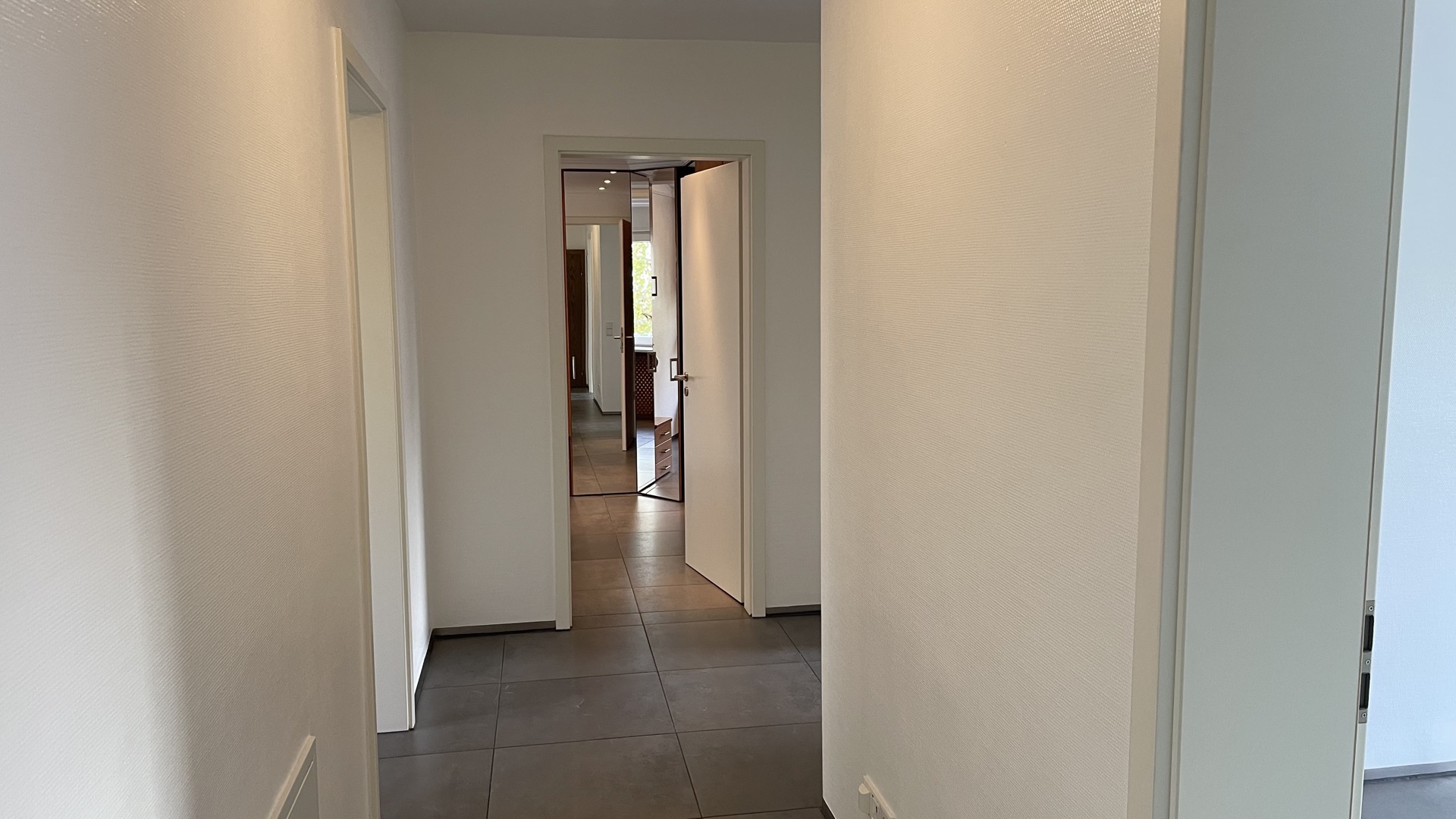 Heller Flur mit Fliesenboden und offenen Türen in einer Wohnimmobilie.
