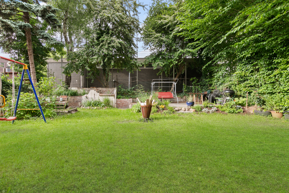 Garten mit Rasenfläche, Schaukel, Sitzbank, Hollywoodschaukel und Bäumen im Hintergrund.