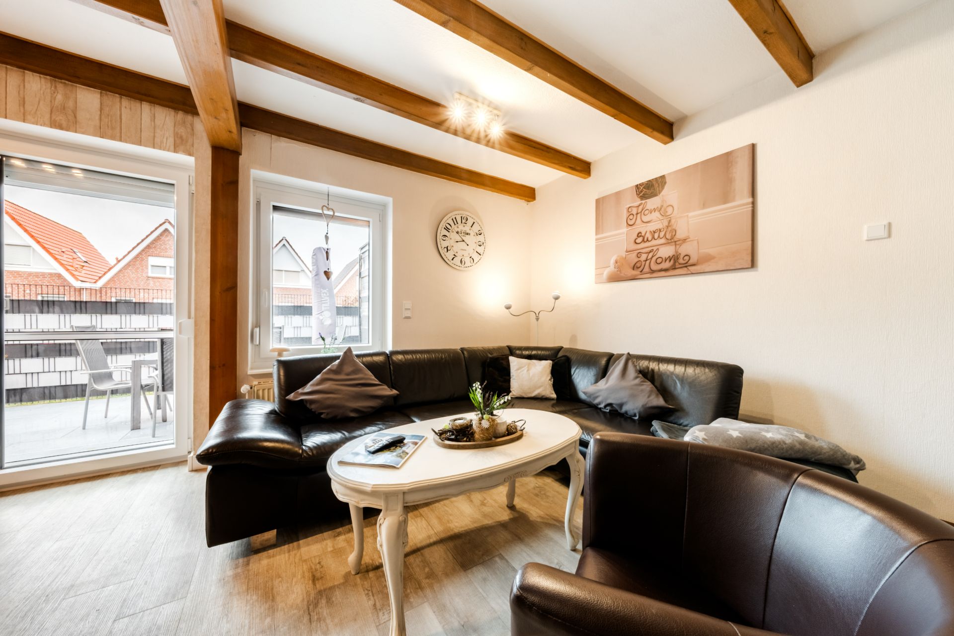 Wohnzimmer mit Ecksofa, Couchtisch, Sessel und Zugang zu einem Balkon.