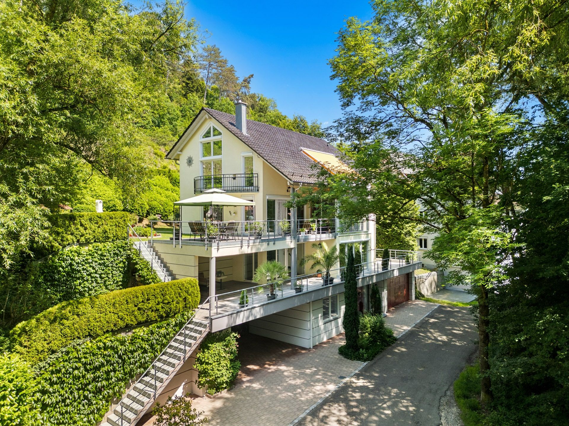 Modernes Wohnhaus mit mehreren Balkonen und viel Grün rundherum.
