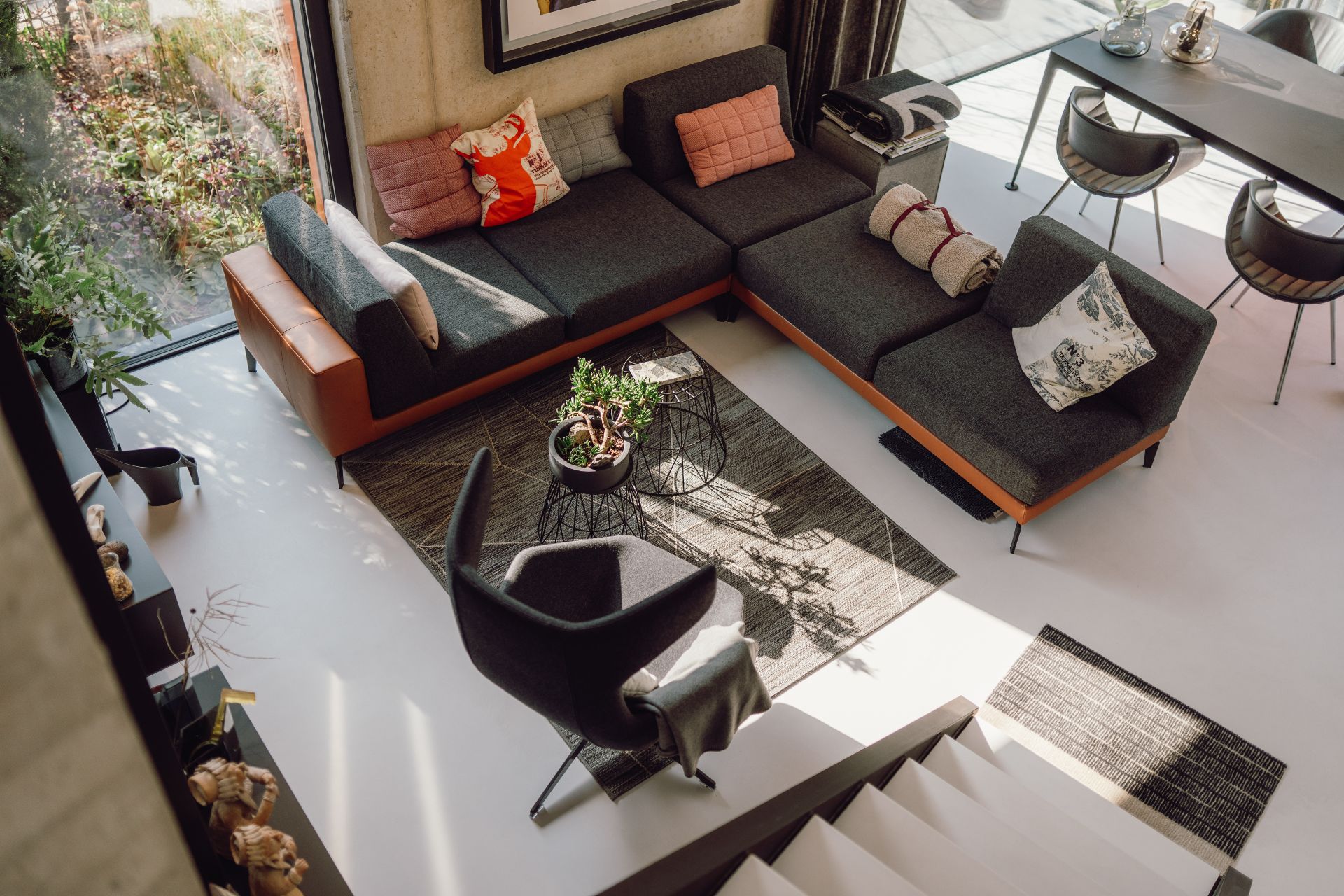 Modernes Wohnzimmer mit Ecksofa, Sessel, Couchtisch und Pflanzen, Blick von oben.