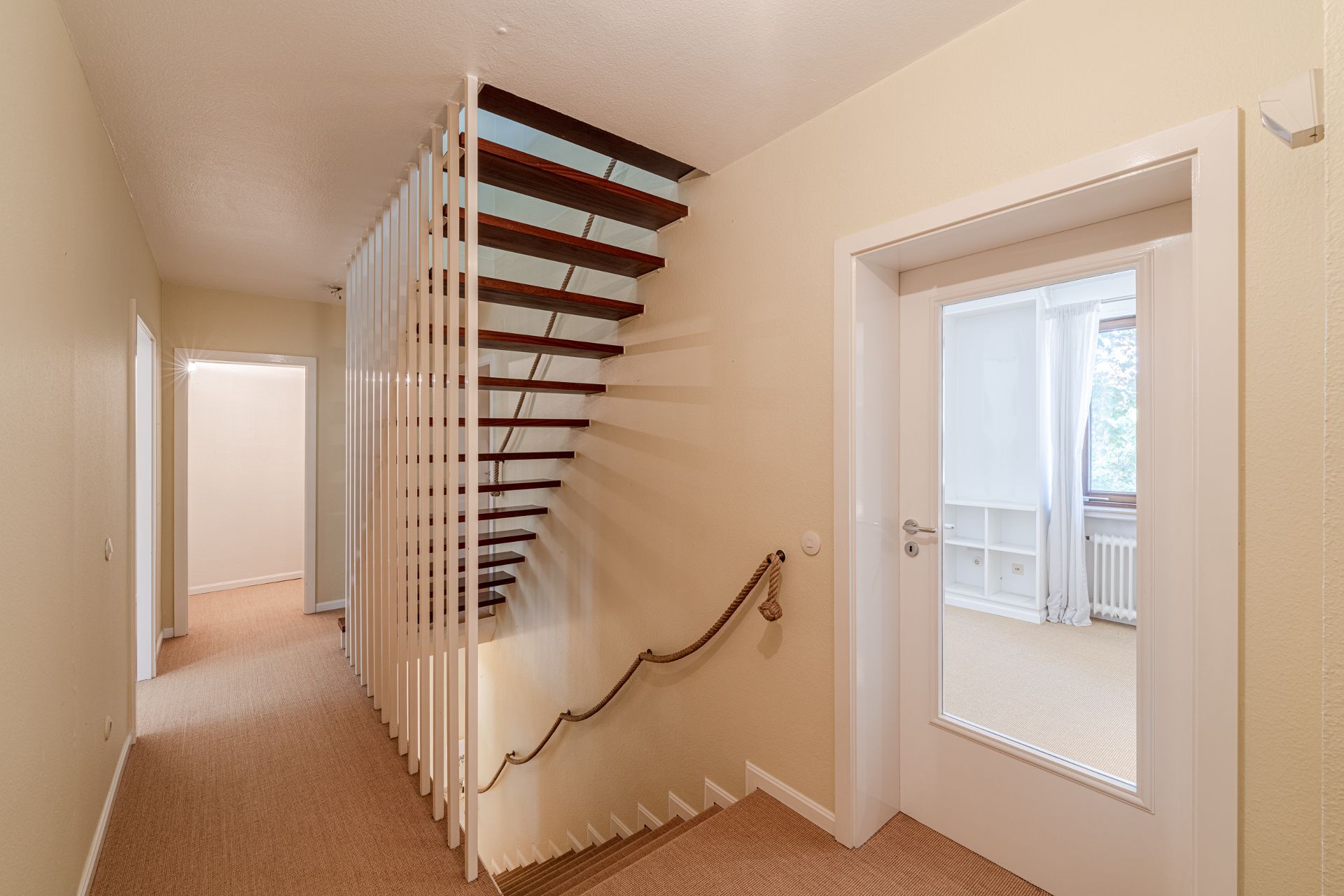 Heller Flur mit Treppe aus Holzstufen und Zugang zu mehreren Zimmern.