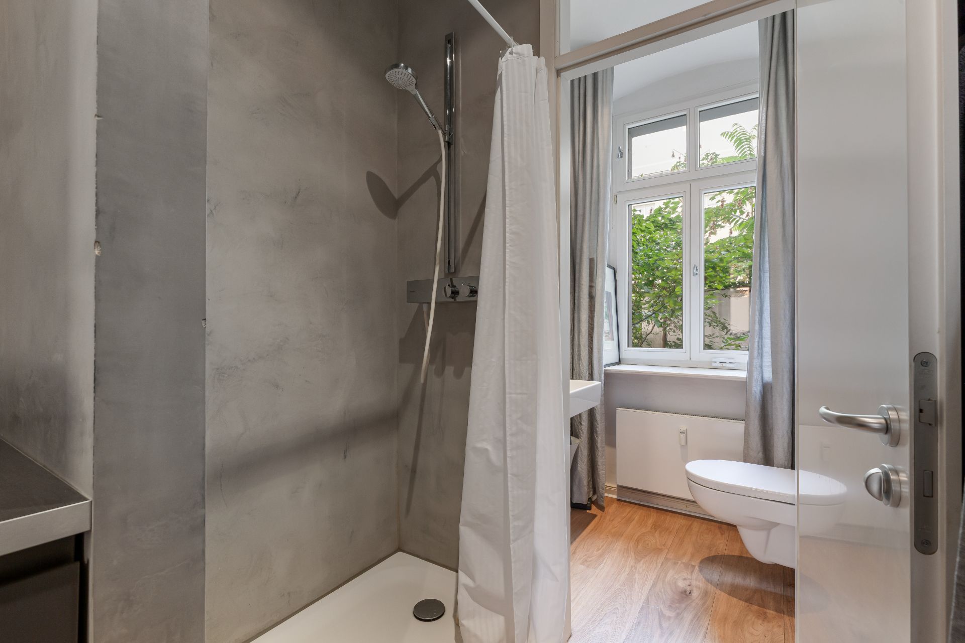Modernes Bad mit Dusche, WC, Fenster und Holzboden.
