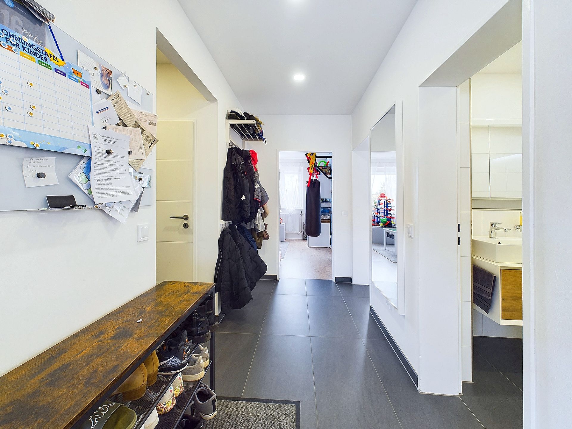 Heller Flur mit Schuhregal, Garderobe, Spiegel und Zugang zu weiteren Zimmern.