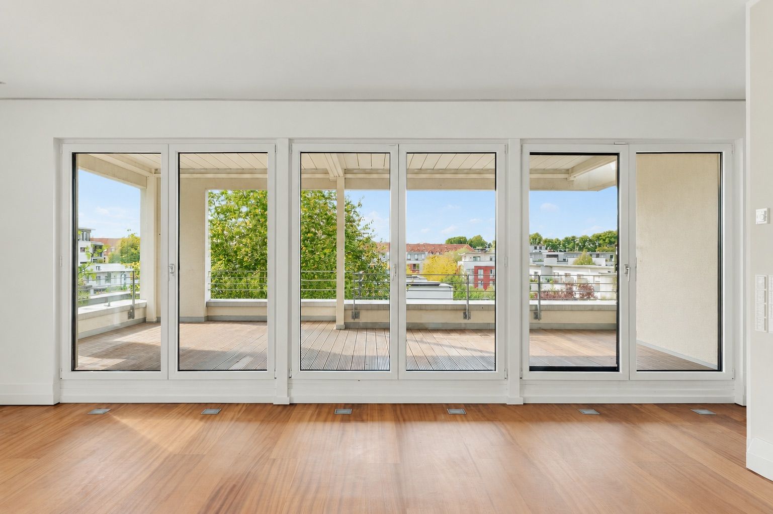Helles Wohnzimmer mit großen Glas-Schiebetüren zu einem Balkon mit Blick ins Grüne.