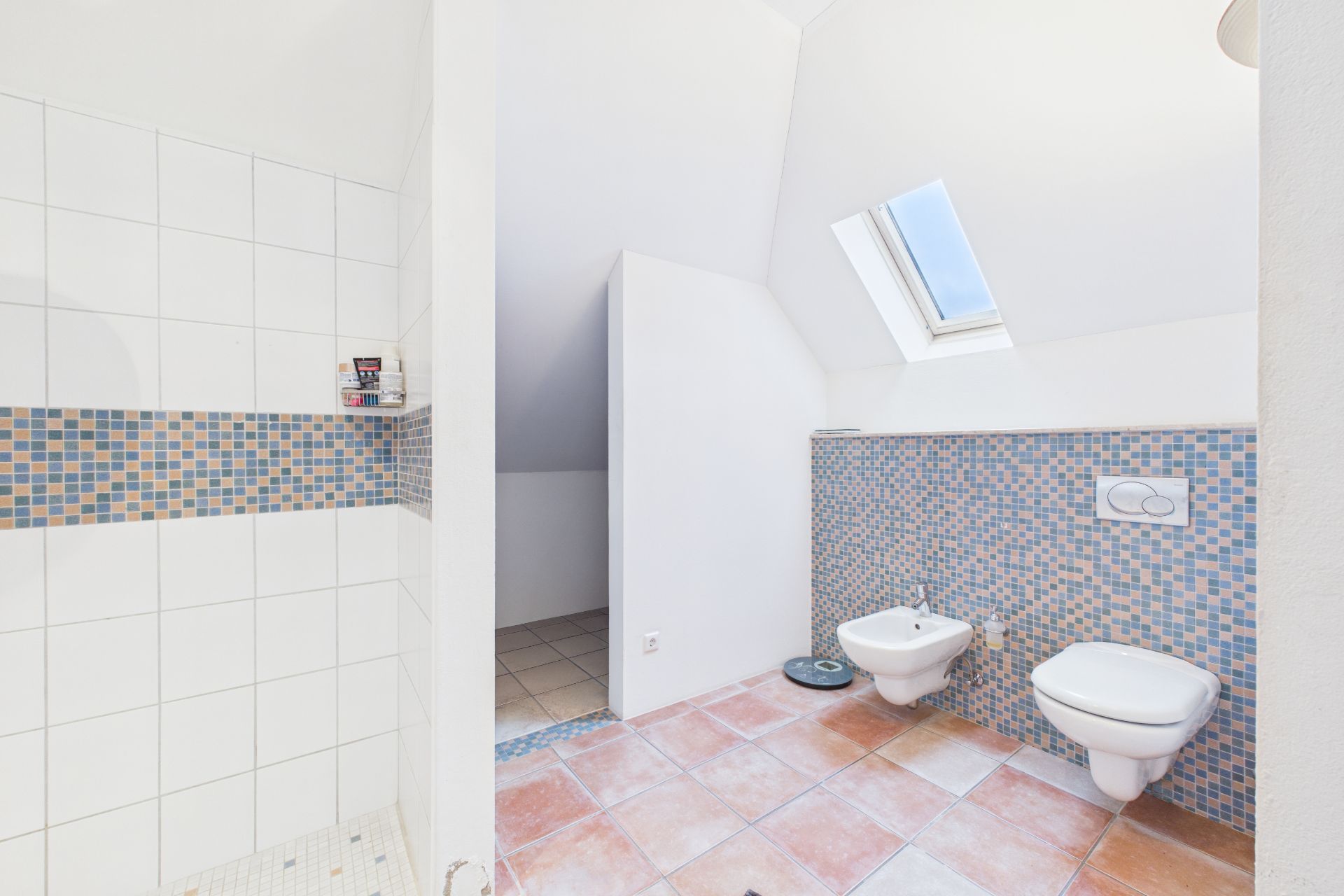Modernes Badezimmer mit Dusche, Bidet, WC und einem Dachfenster.