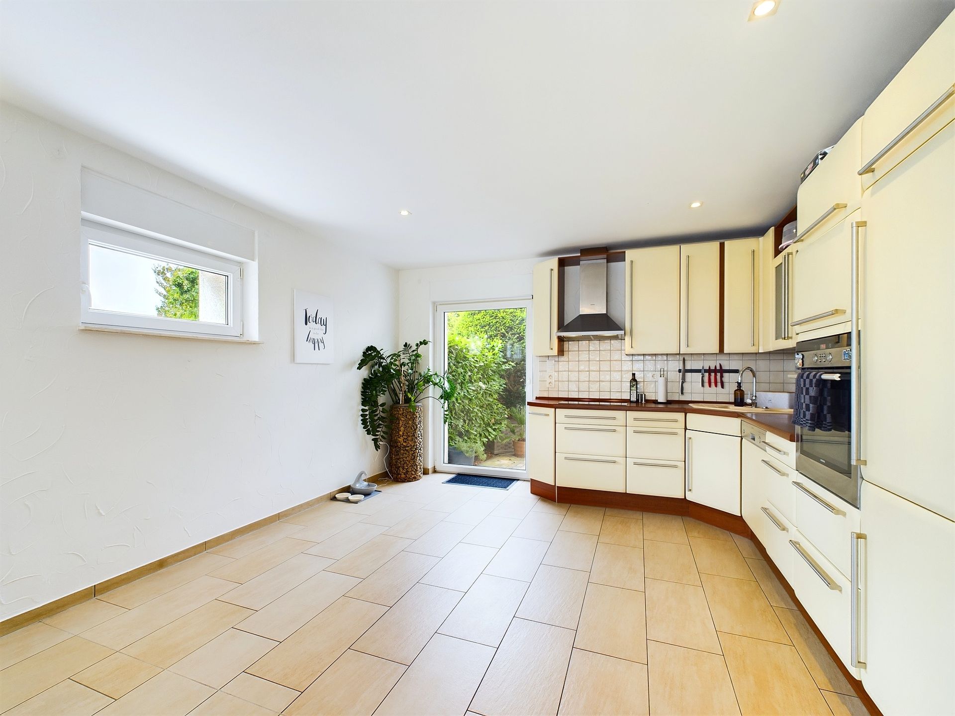 Helle, moderne Küche mit weißen Schränken, Pflanzen und Zugang zum Garten.