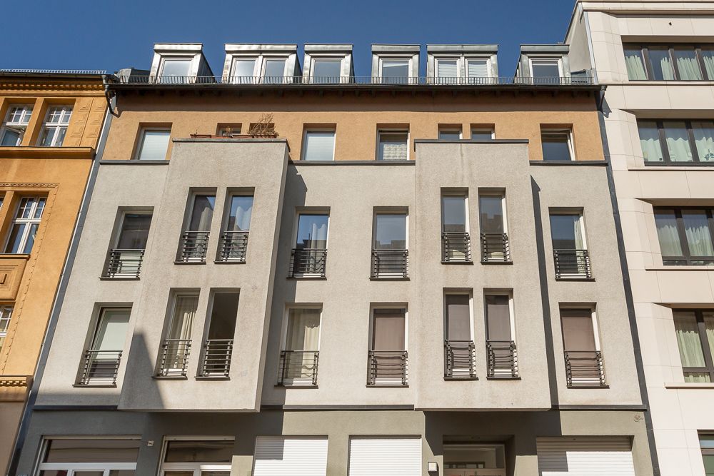 Moderne Wohnhausfassade mit vielen Fenstern und kleinen Balkonen.