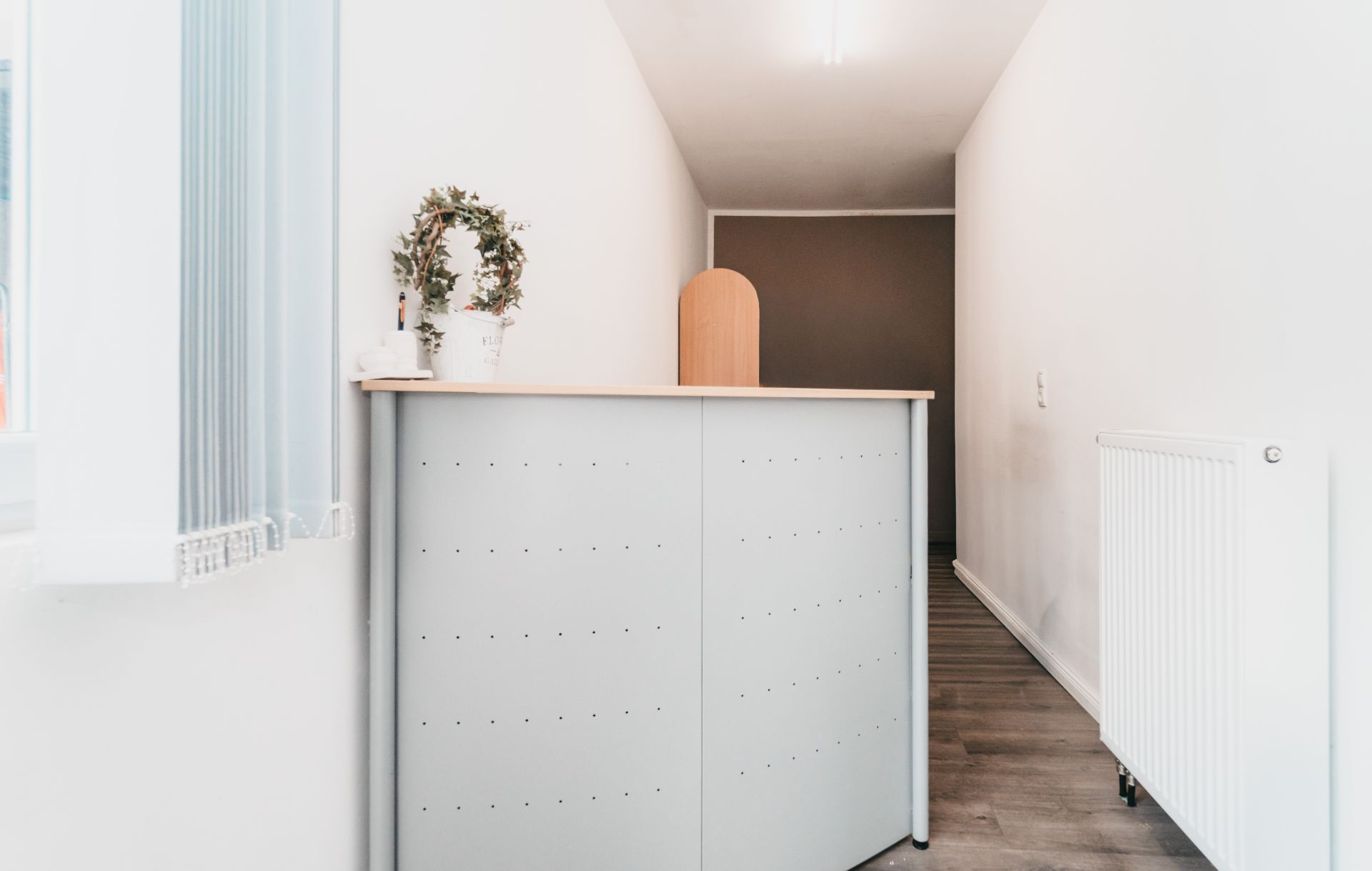 Heller Flur mit grauer Theke, Heizkörper und Topfpflanze auf der Theke.