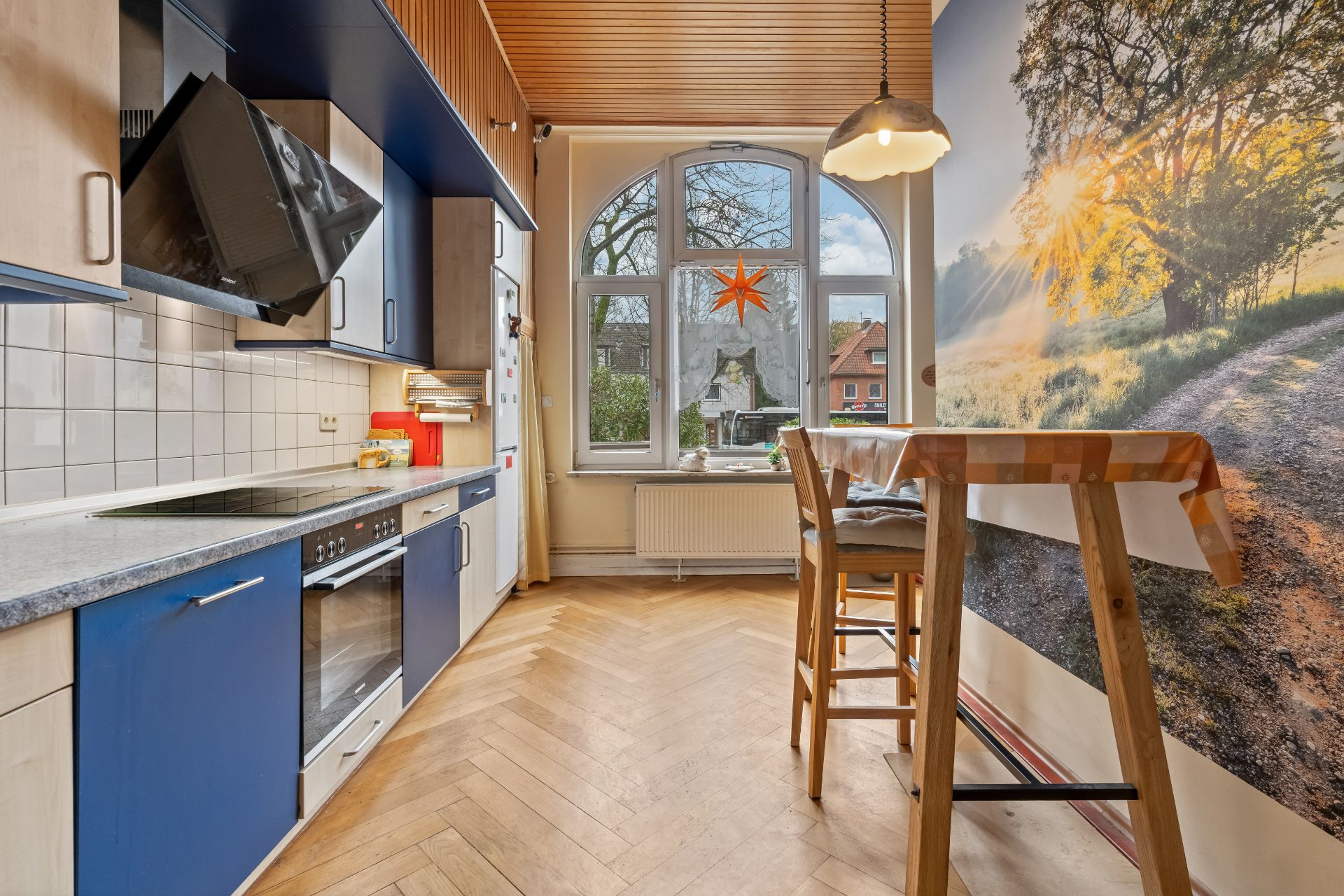 Moderne Küche mit blauem Schrank, Esstisch und großem Fenster mit Blick nach draußen.