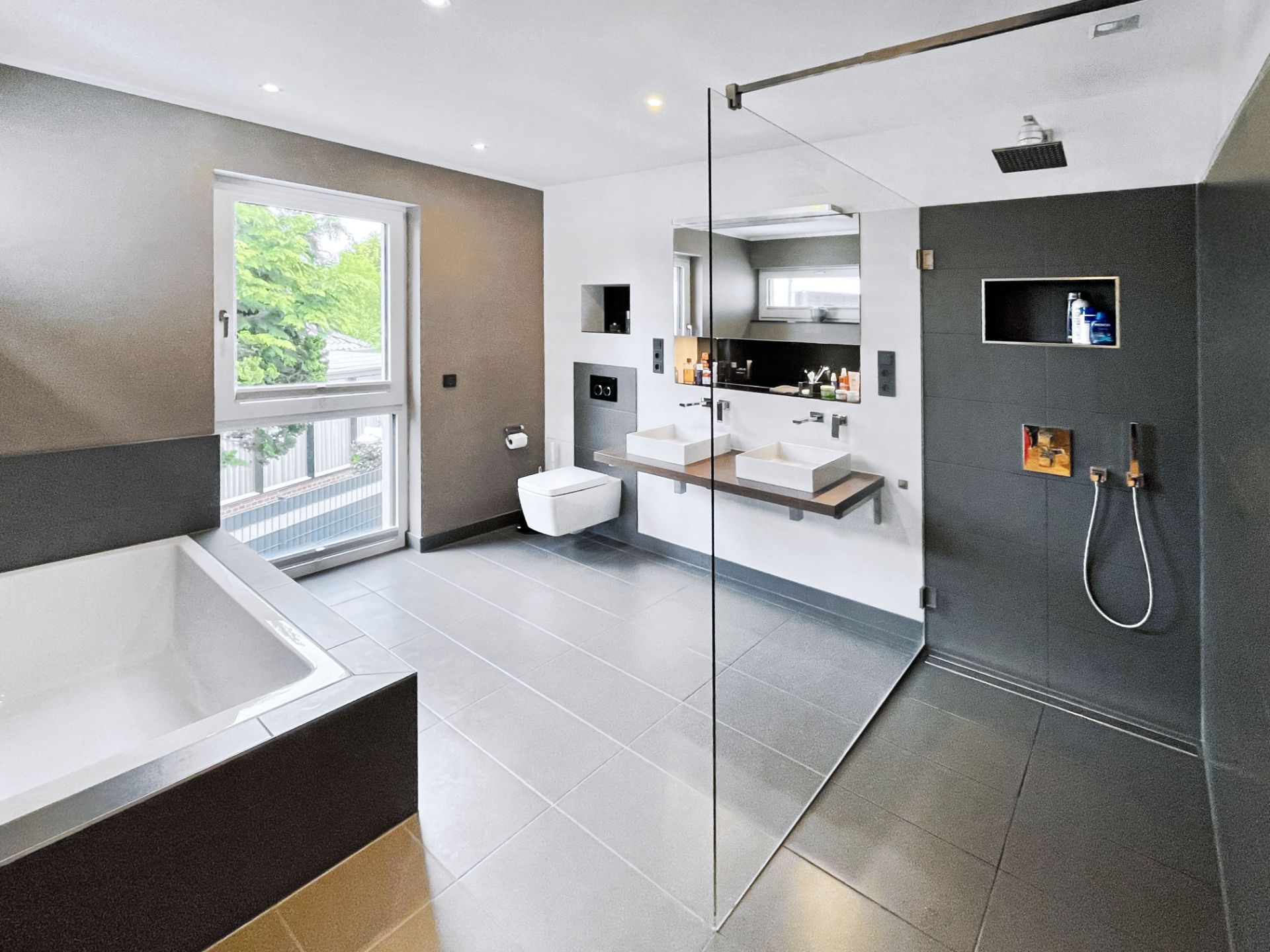 Modernes Badezimmer mit großer Dusche, Badewanne, Doppelwaschbecken und Fenster.