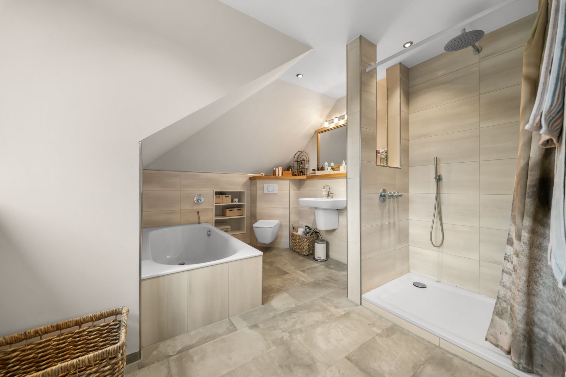 Modernes Badezimmer mit Badewanne, Dusche, WC und Waschbecken unter einer Dachschräge.