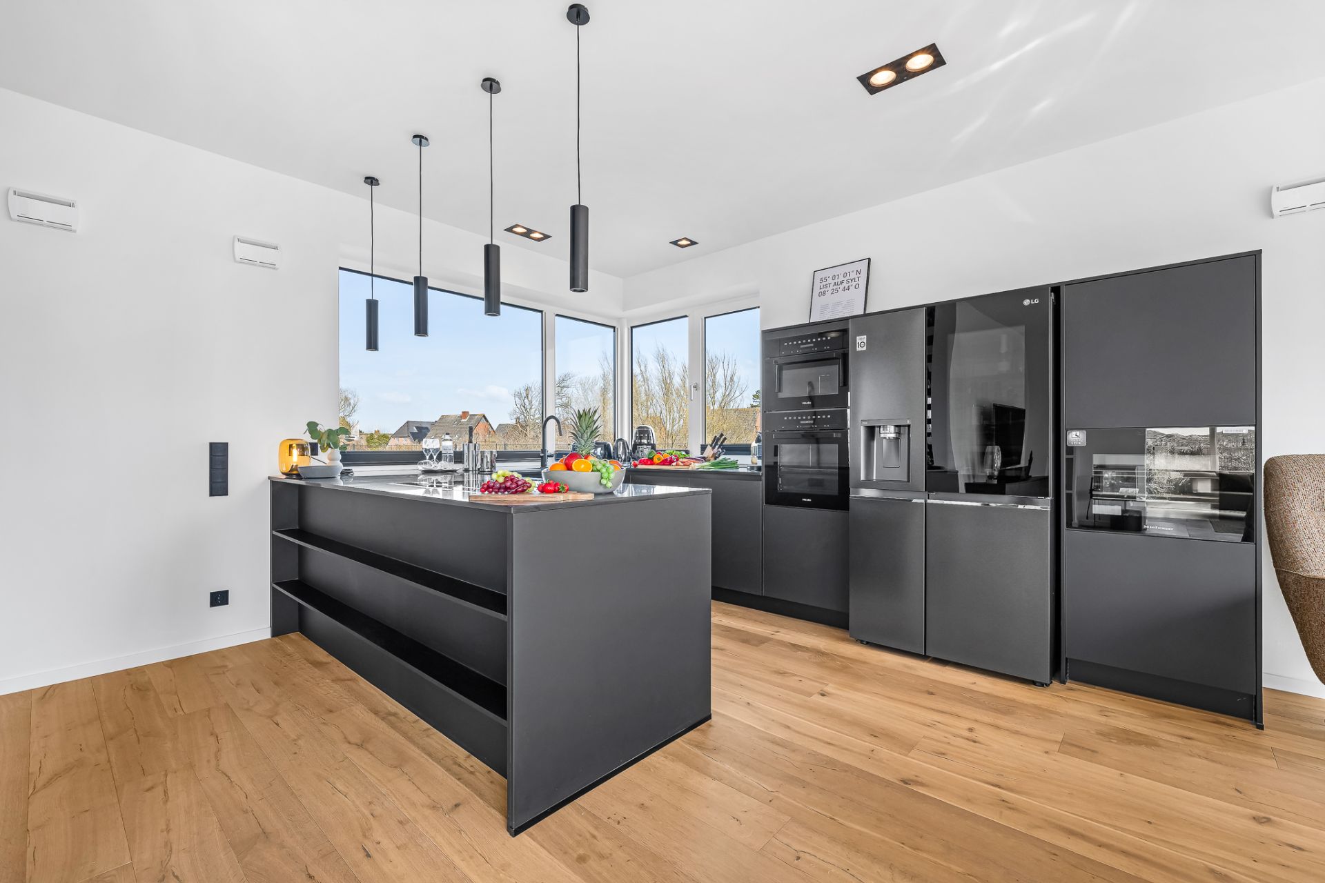 Moderne Küche mit dunklen Schränken, Kücheninsel und großem Fenster, Holzfußboden.