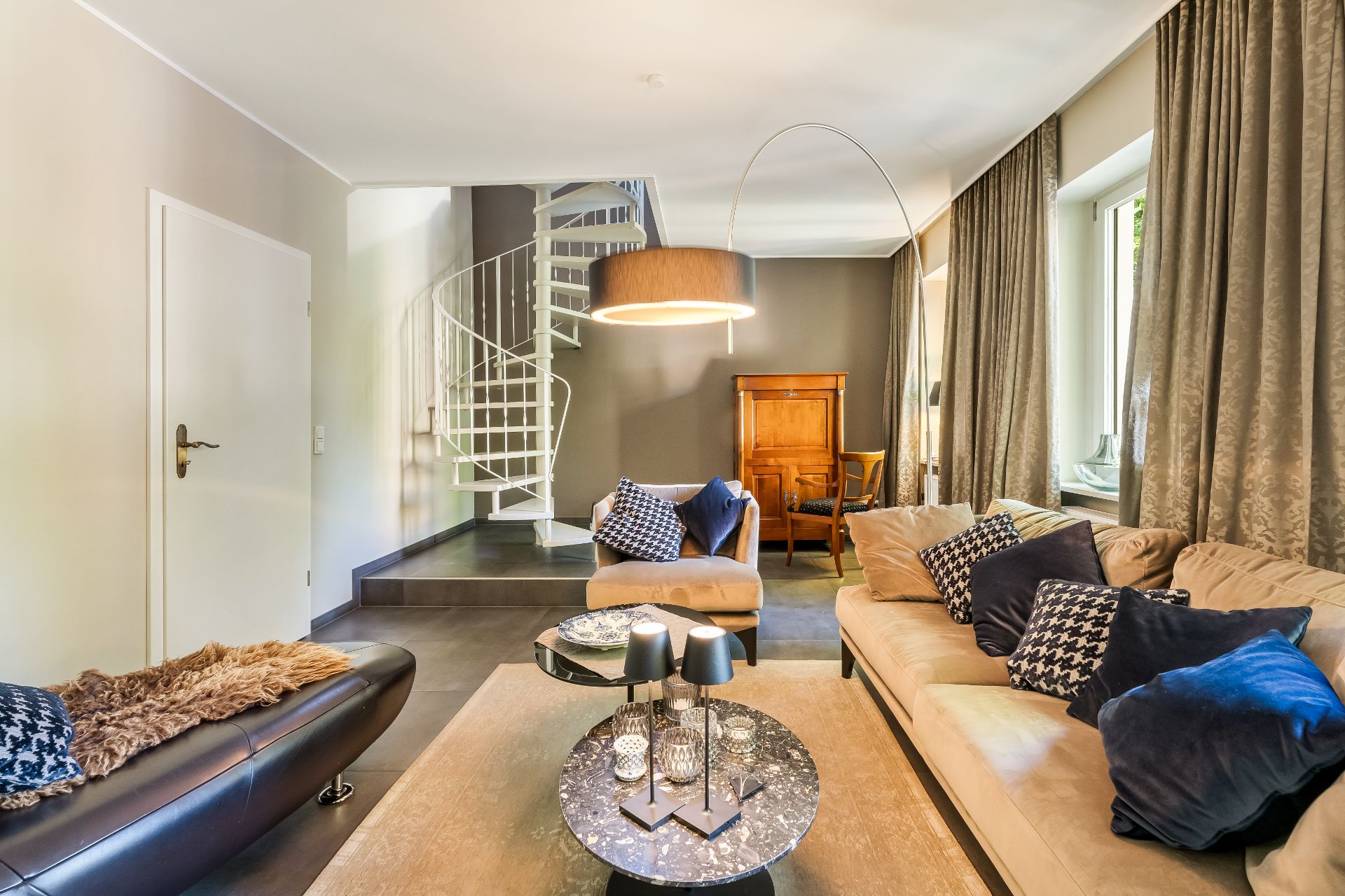 Modernes Wohnzimmer mit Sofas, Couchtisch, Stehlampe und Wendeltreppe.