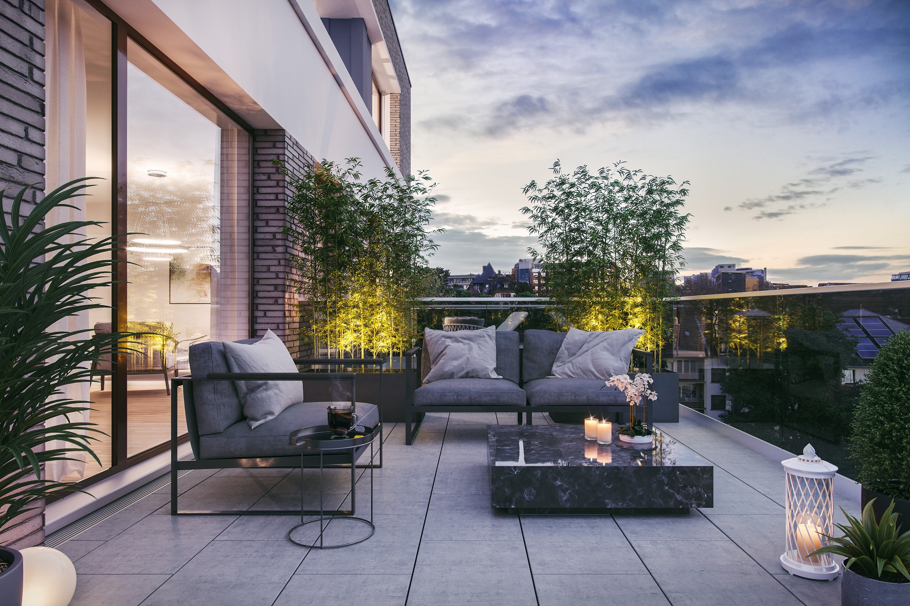 Moderne Terrasse mit Sofas, Couchtisch, Pflanzen und Kerzen bei Abenddämmerung. Haus kaufen Infos und Tipps