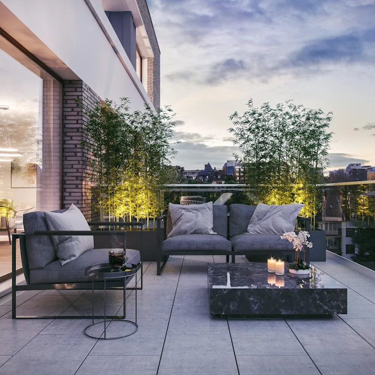 Moderne Terrasse mit Sofas, Couchtisch, Pflanzen und Kerzen bei Abenddämmerung. Haus kaufen Infos und Tipps