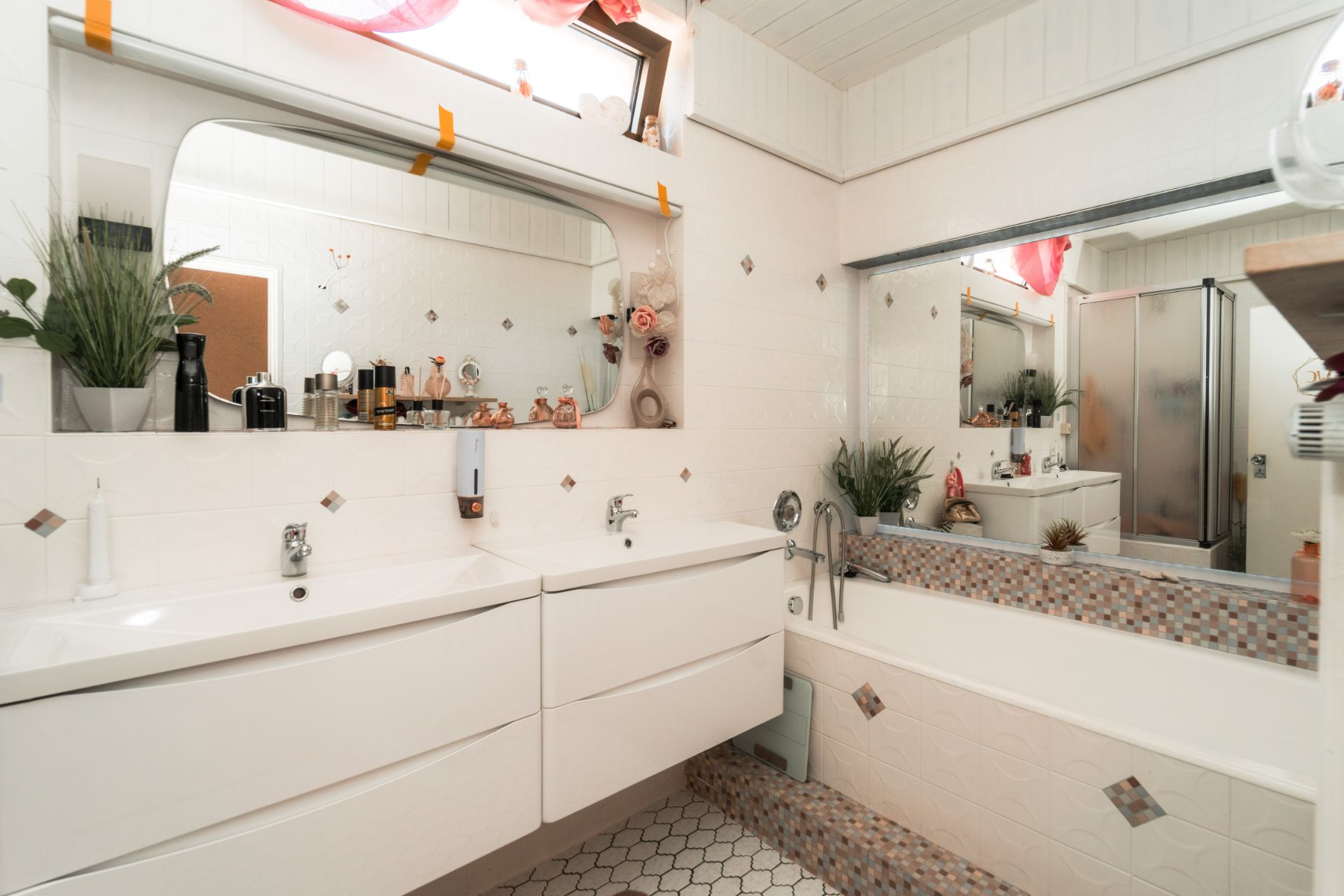 Modernes Badezimmer mit Doppelwaschbecken, Badewanne, Spiegel und Pflanzen.