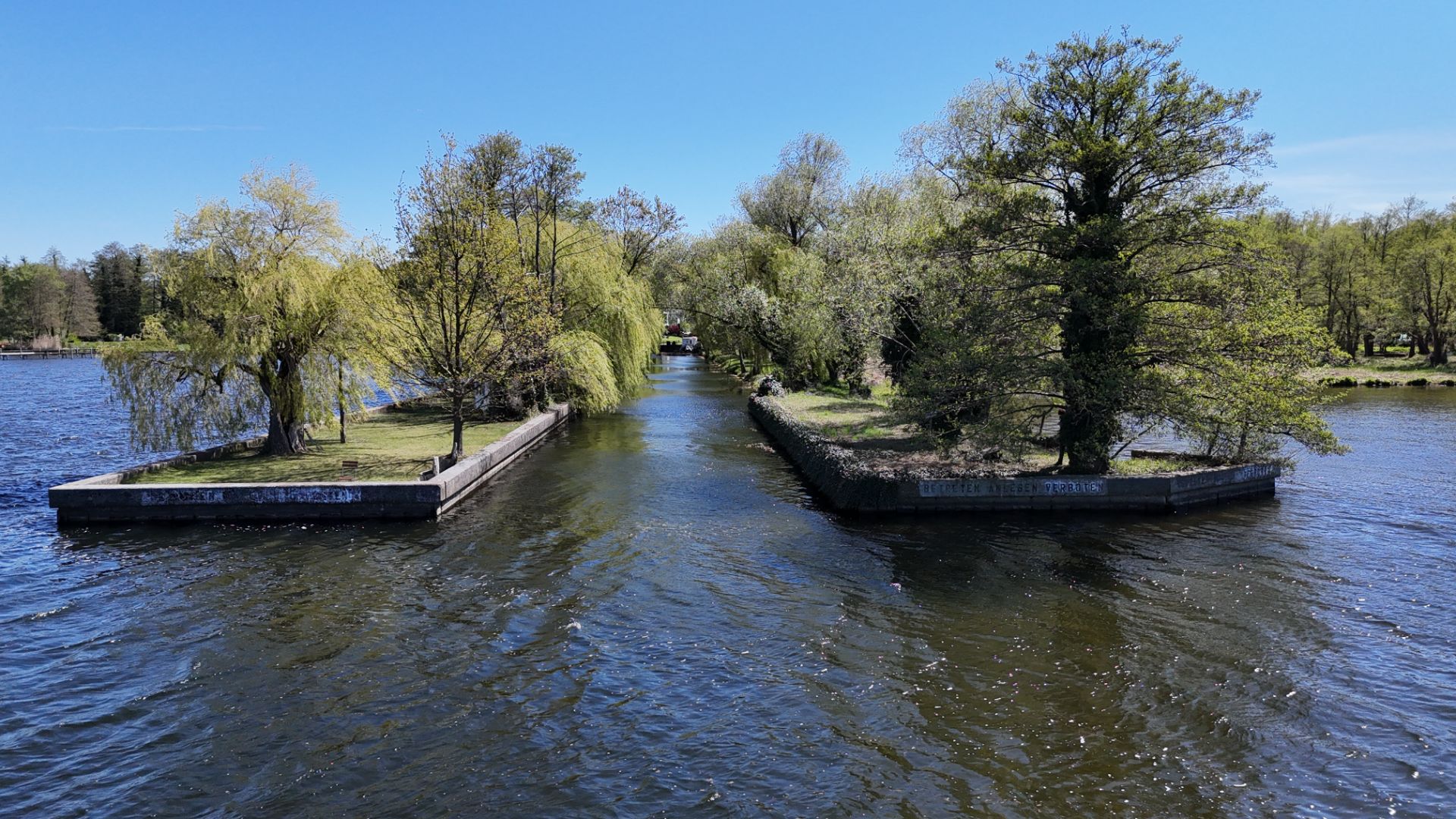 Zwei begrünte Landzungen ragen ins Wasser, getrennt durch eine Wasserstraße.