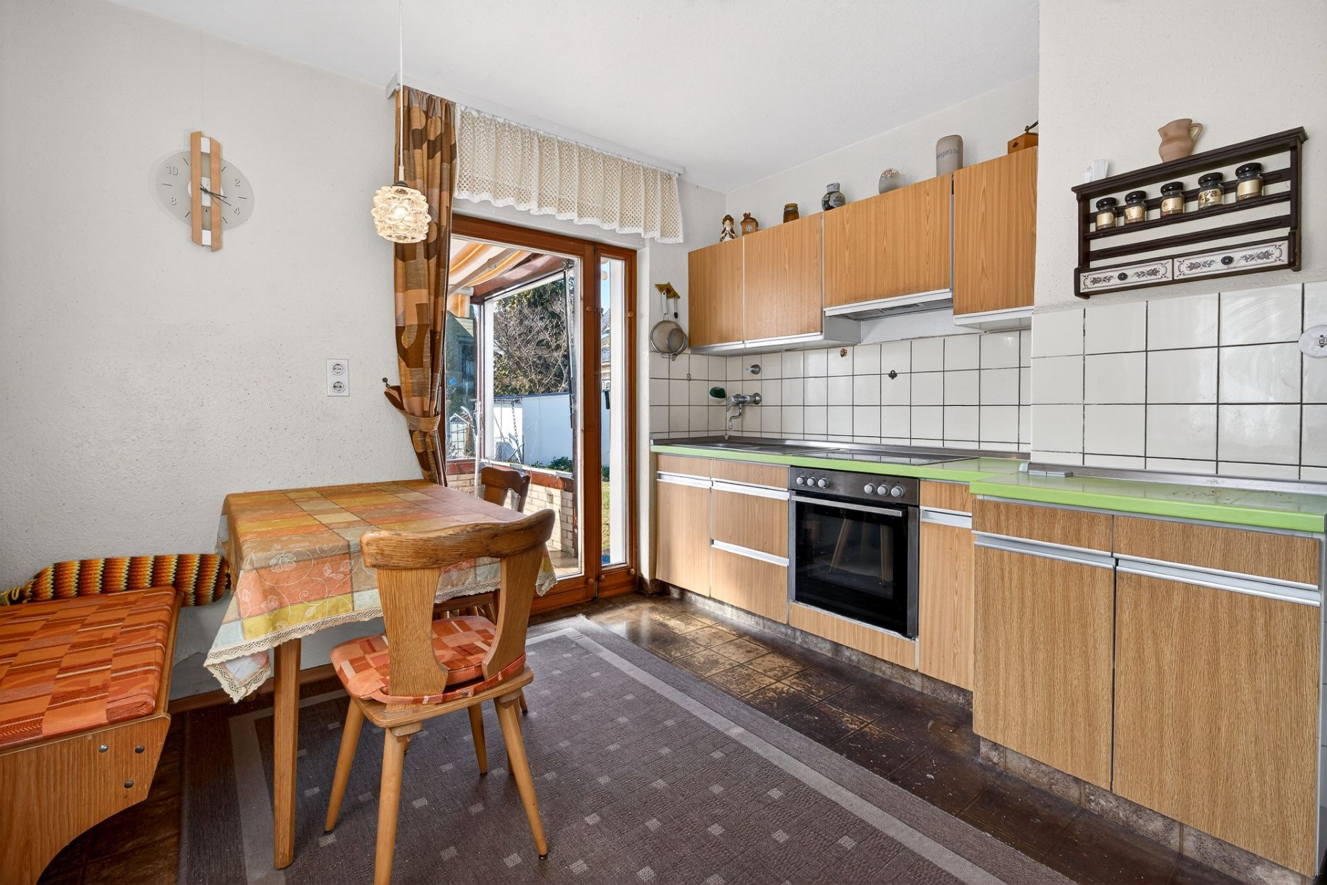 Helle Küche mit Holzmöbeln, Esstisch, Eckbank und Zugang zur Terrasse.