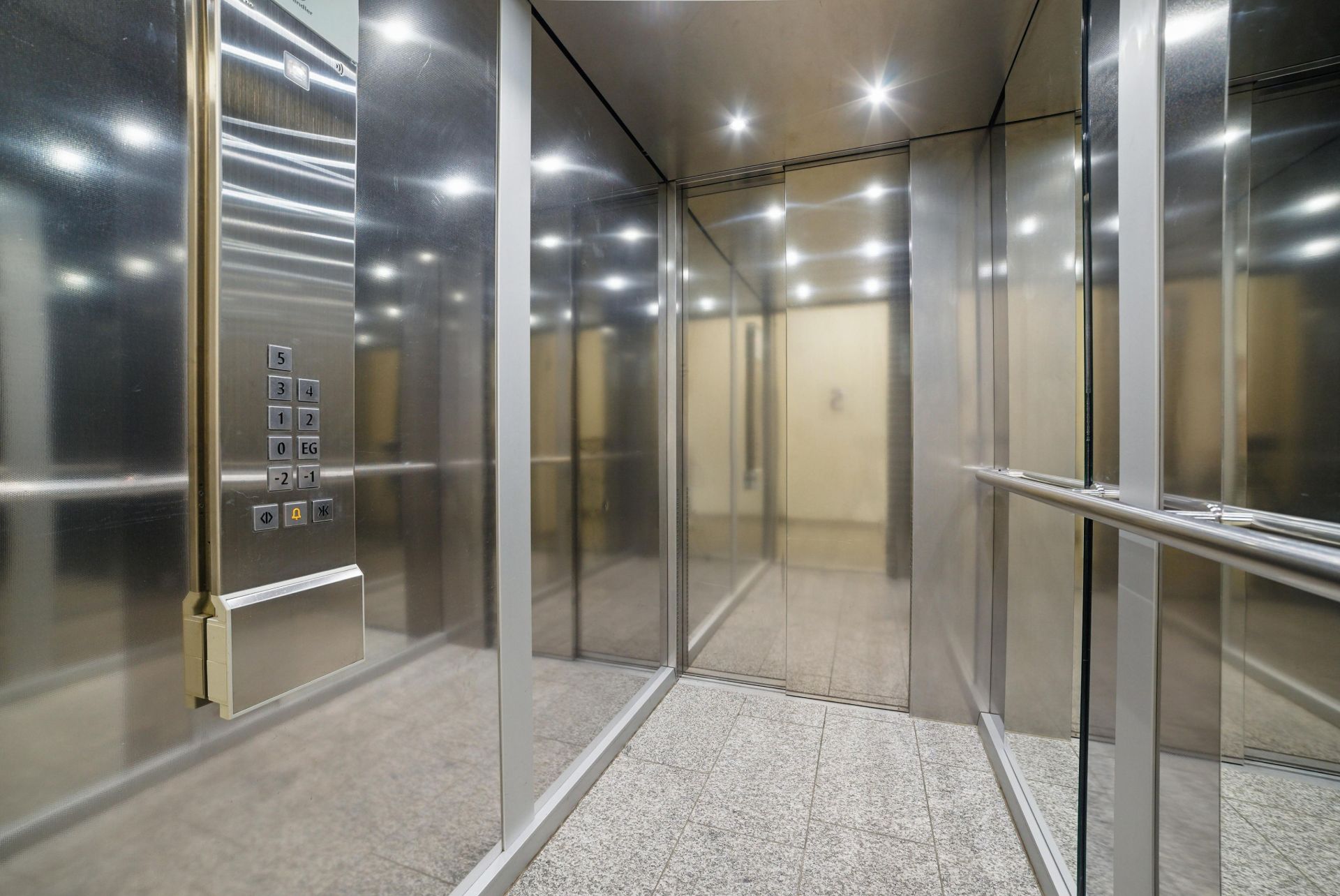 Moderner Aufzug mit Spiegelwänden und Bedienfeld an der linken Seite.