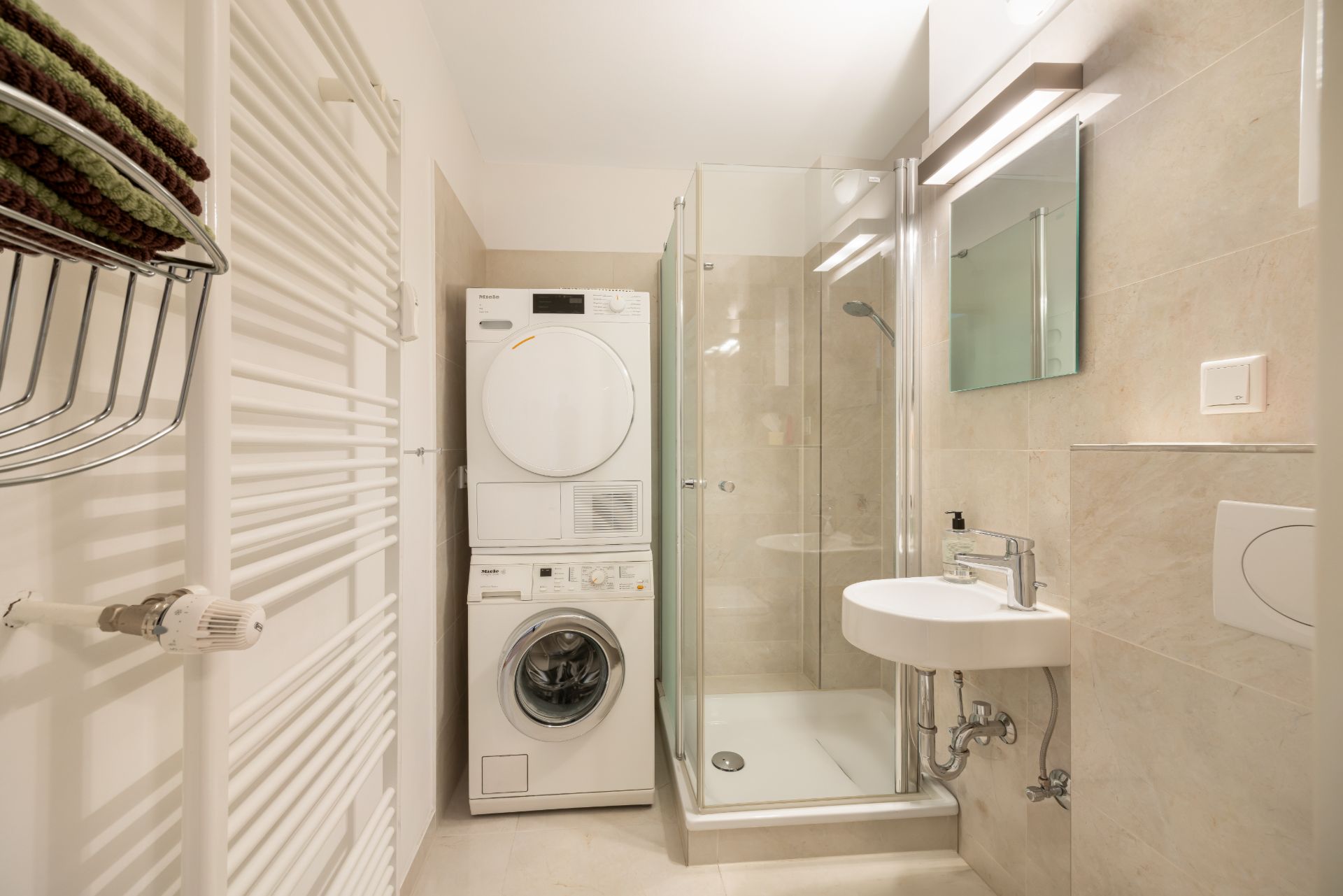 Modernes Badezimmer mit Dusche, Waschbecken, Waschmaschine und Trockner.