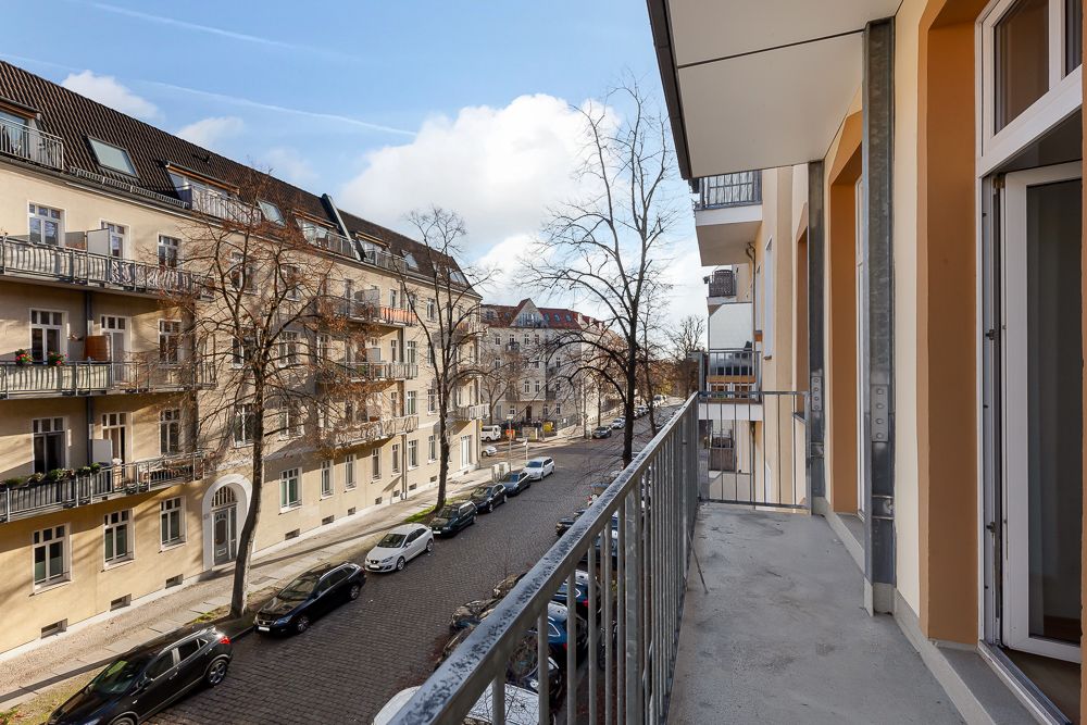 Balkon mit Blick auf eine ruhige Wohnstraße und gegenüberliegende Altbauten.
