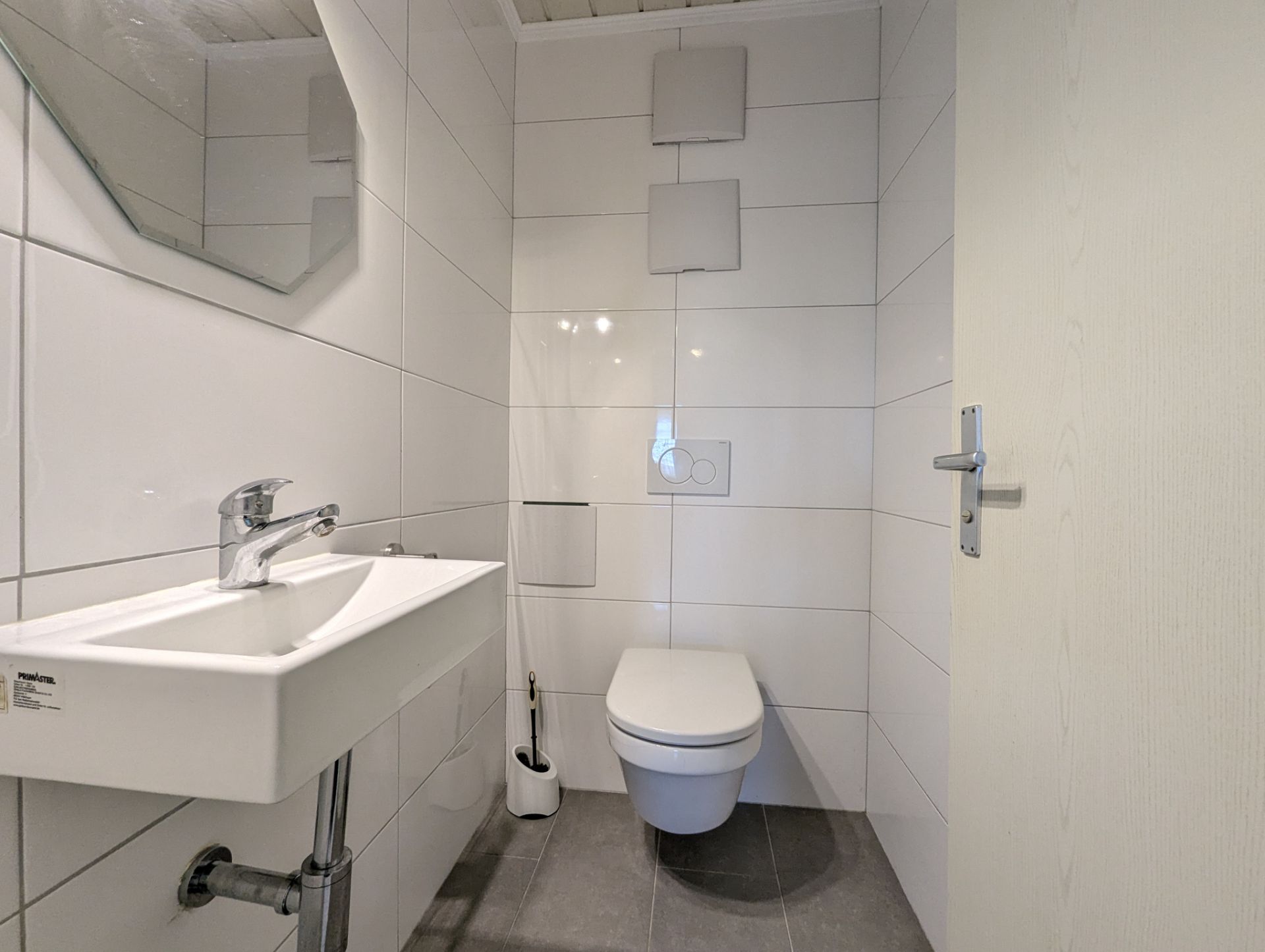 Kleines, modernes Bad mit Wand-WC, Waschbecken und Spiegel.