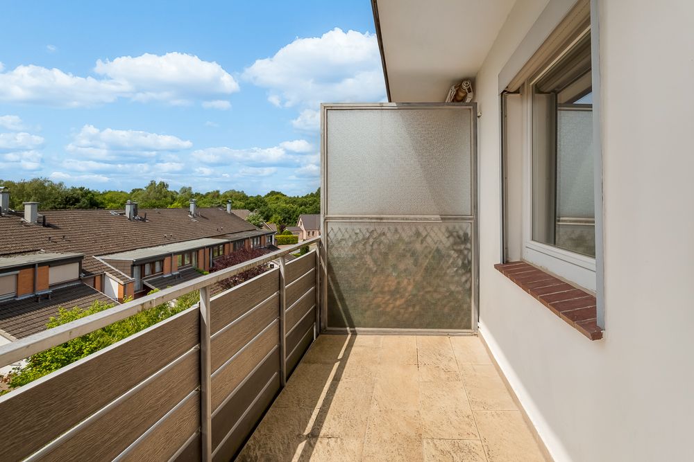Balkon mit Metallgeländer und Sichtschutz, Blick auf Wohnhäuser und Bäume.