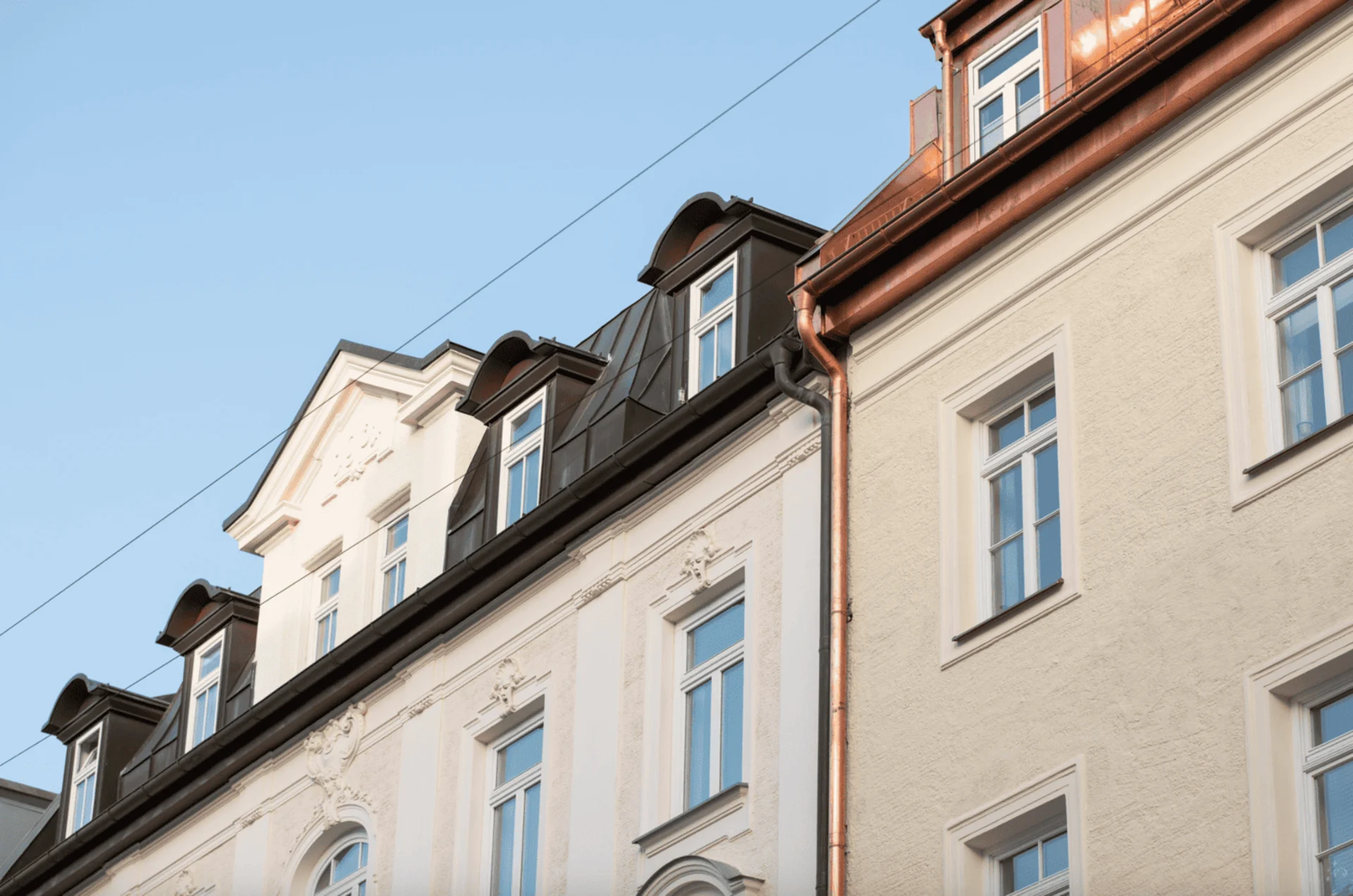 Fassaden von Wohngebäuden mit vielen Fenstern und dekorativen Elementen bei Tageslicht.