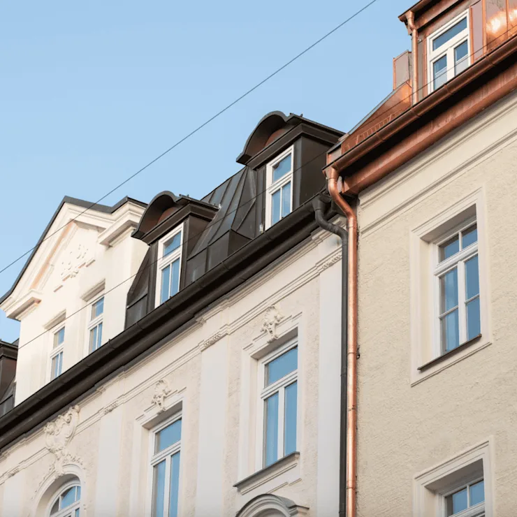 Fassaden von Wohngebäuden mit vielen Fenstern und dekorativen Elementen bei Tageslicht.