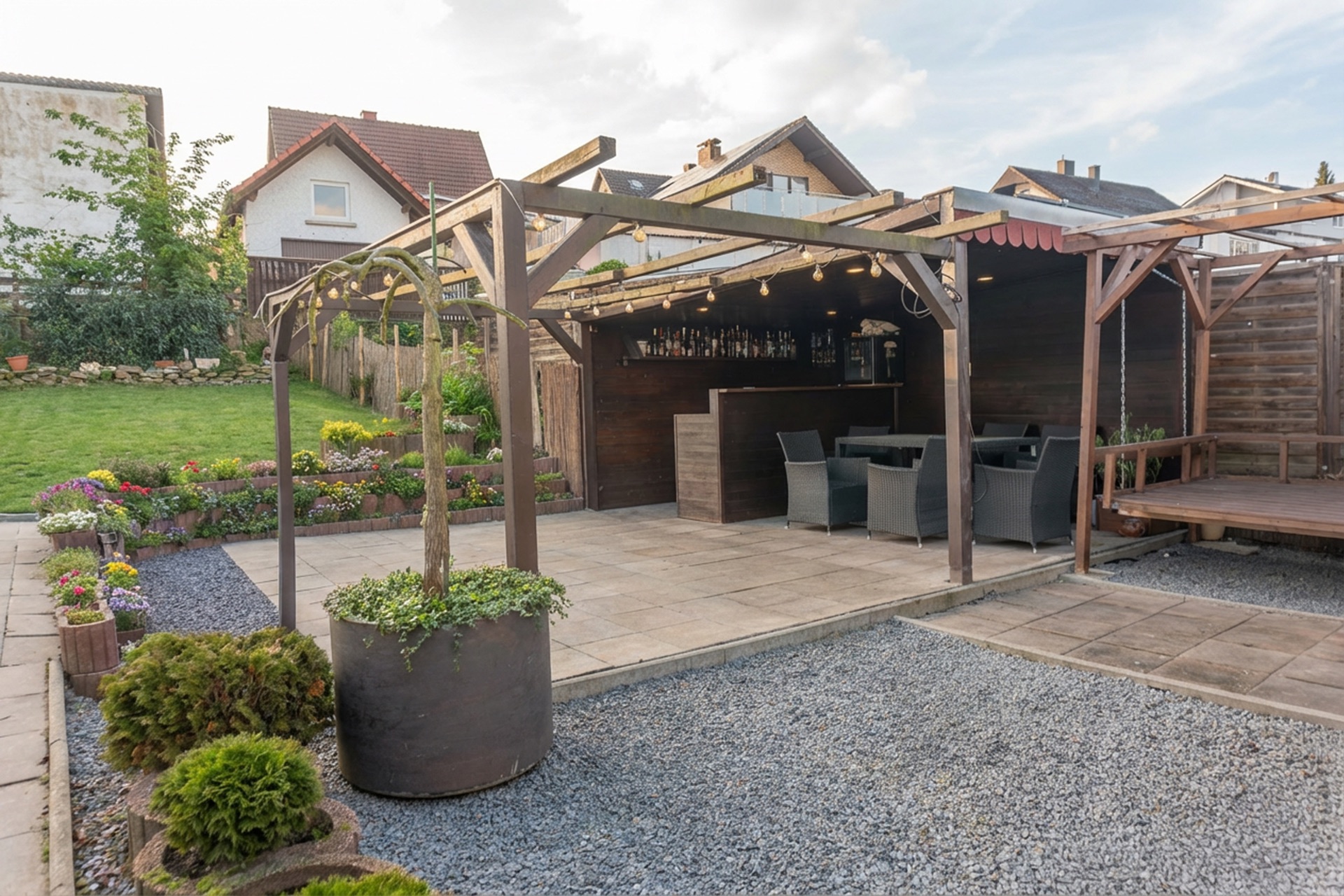 Überdachte Terrasse mit Sitzmöbeln und kleinem Barbereich im Garten eines Wohnhauses.