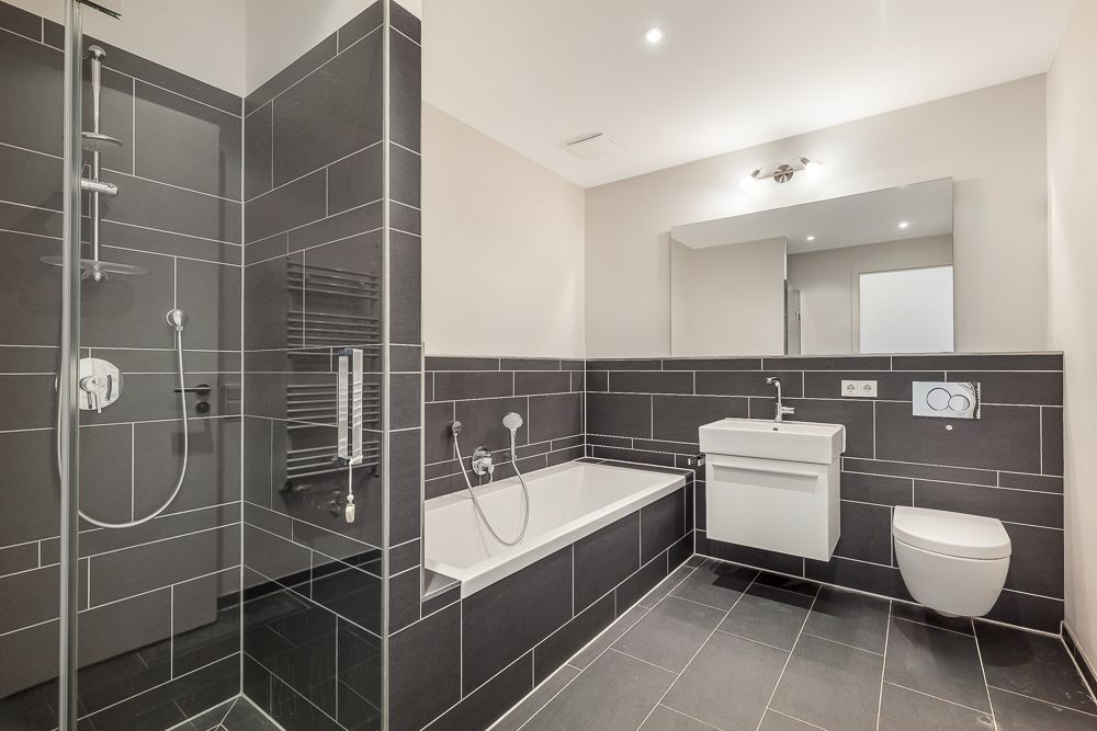 Modernes Badezimmer mit Dusche, Badewanne, Waschbecken, WC und großem Spiegel.