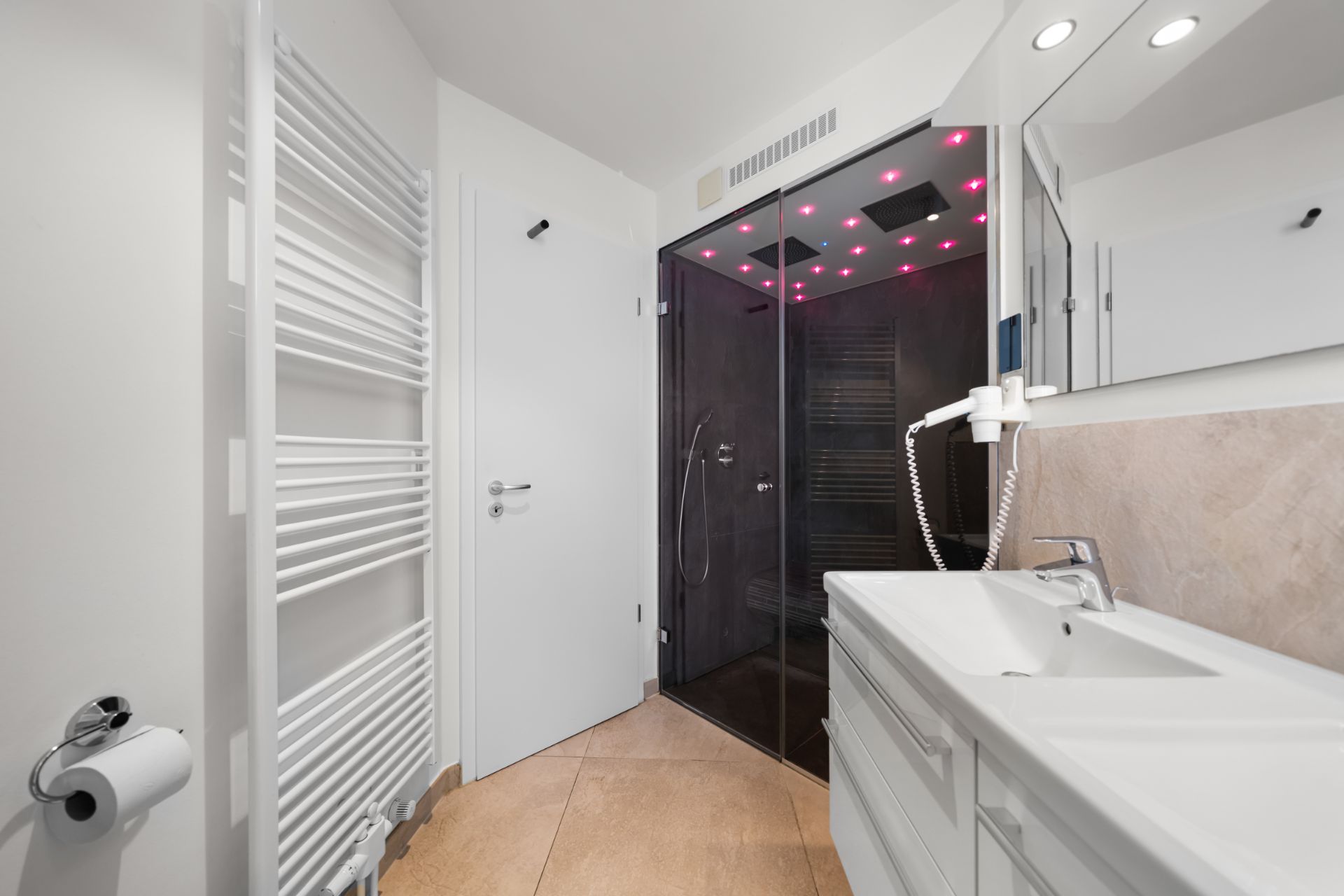 Modernes Badezimmer mit Dusche, Spiegel, Waschbecken und Handtuchheizkörper.