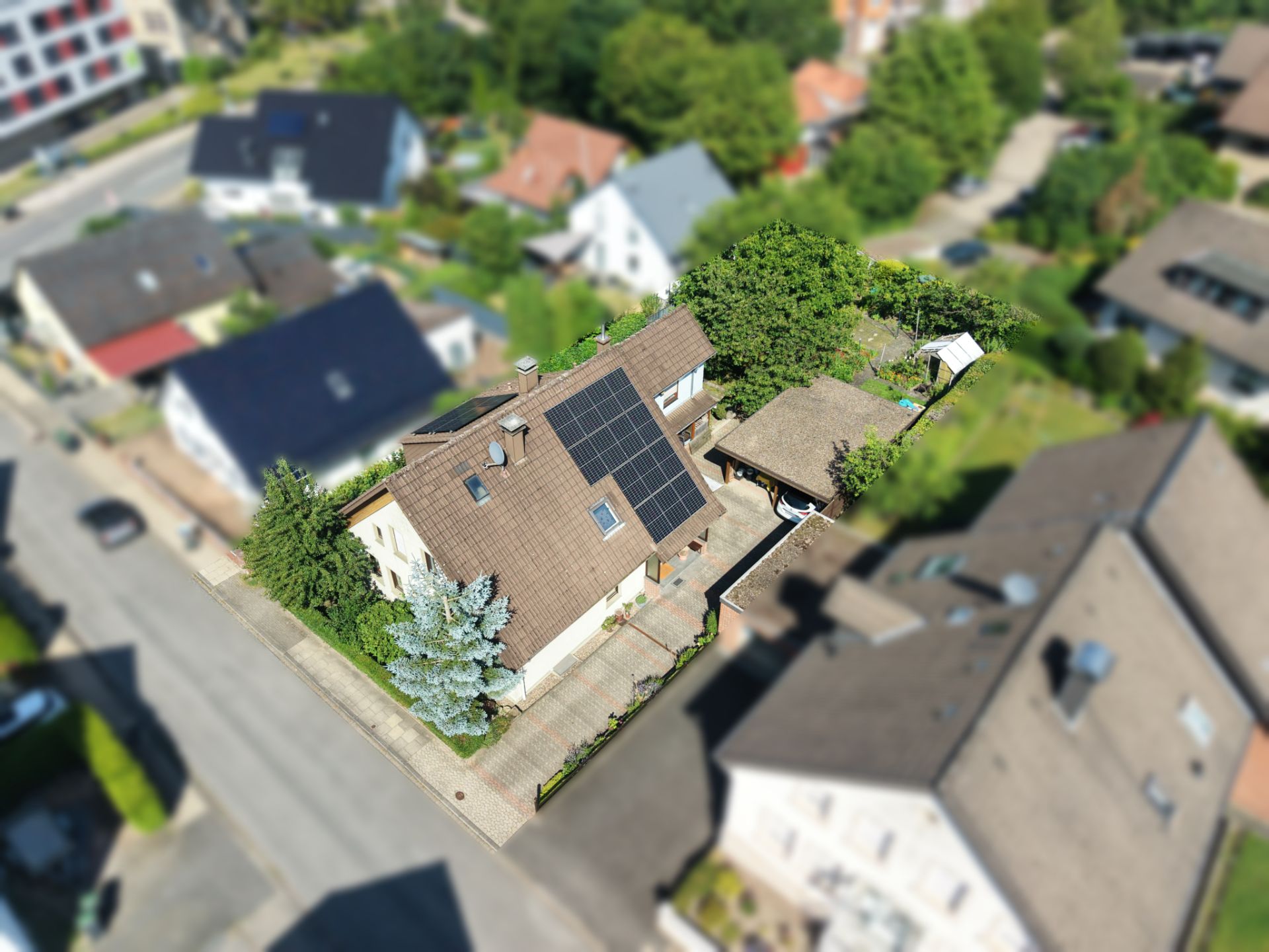 Luftaufnahme eines Einfamilienhauses mit Solarpanels auf dem Dach und Garten.