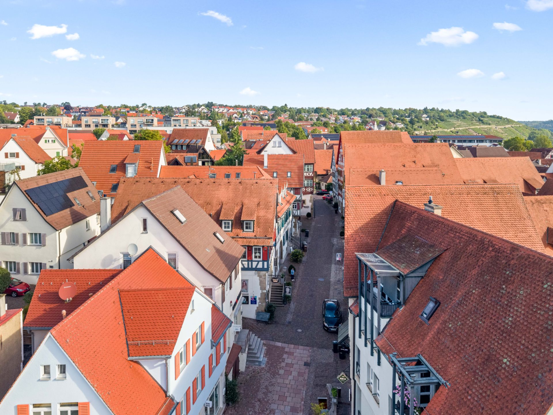 Luftaufnahme von Wohnhäusern mit roten Dächern und einer schmalen gepflasterten Straße.