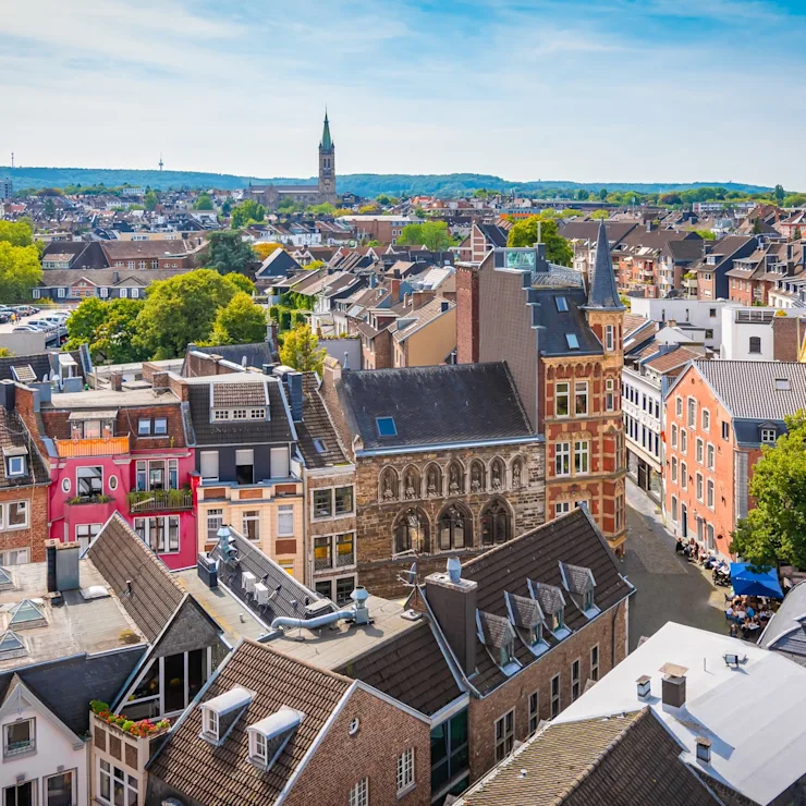 Blick über eine Altstadt mit bunten Häusern und Kirchtürmen bei klarem Himmel.