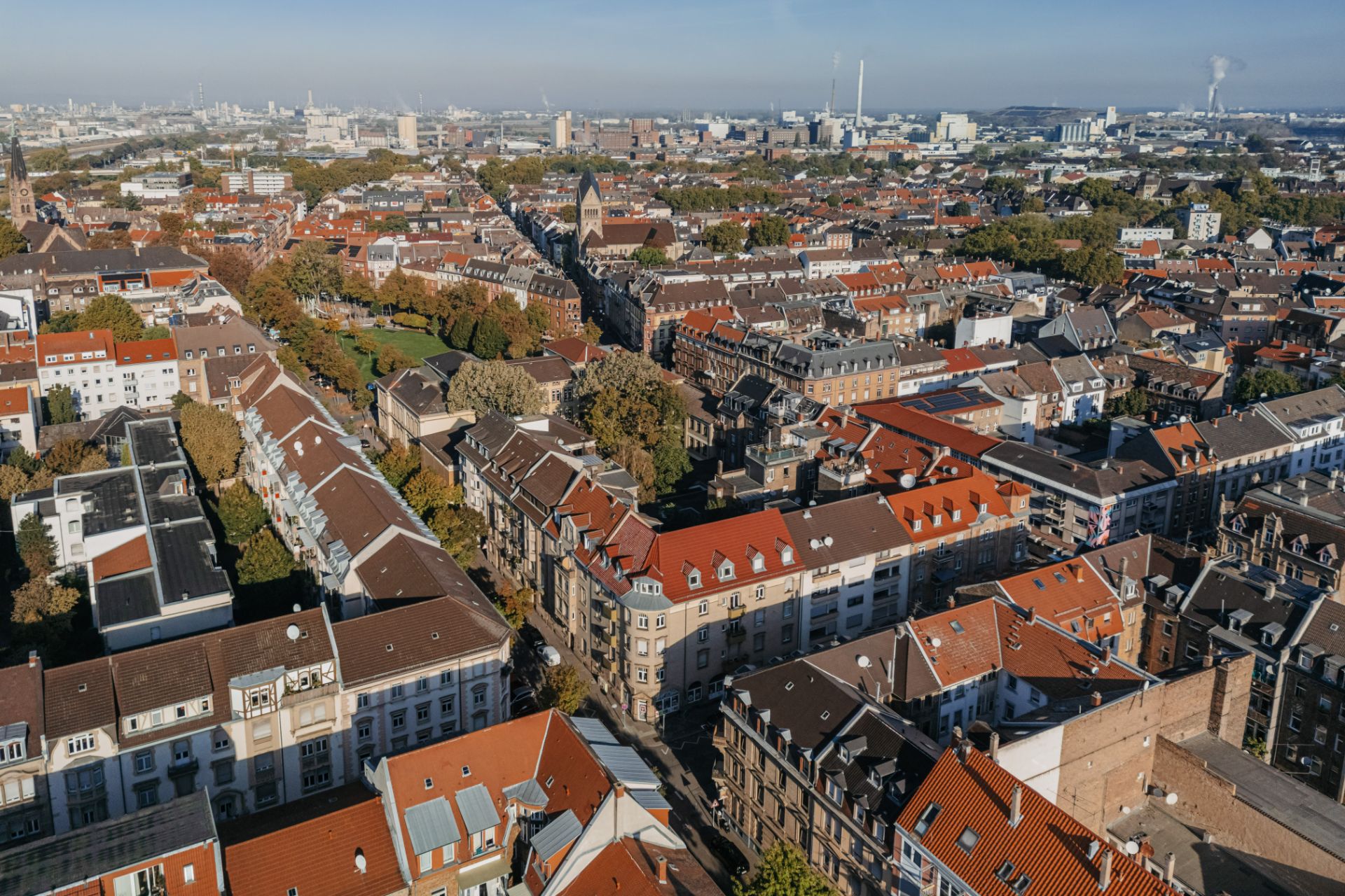 Blick über ein Wohnviertel mit vielen Häusern und roten Dächern, umgeben von Bäumen.