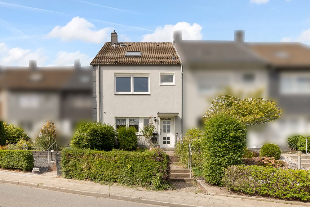 Zweistöckiges Wohnhaus mit Vorgarten, Treppe zum Eingang und umliegenden Büschen.