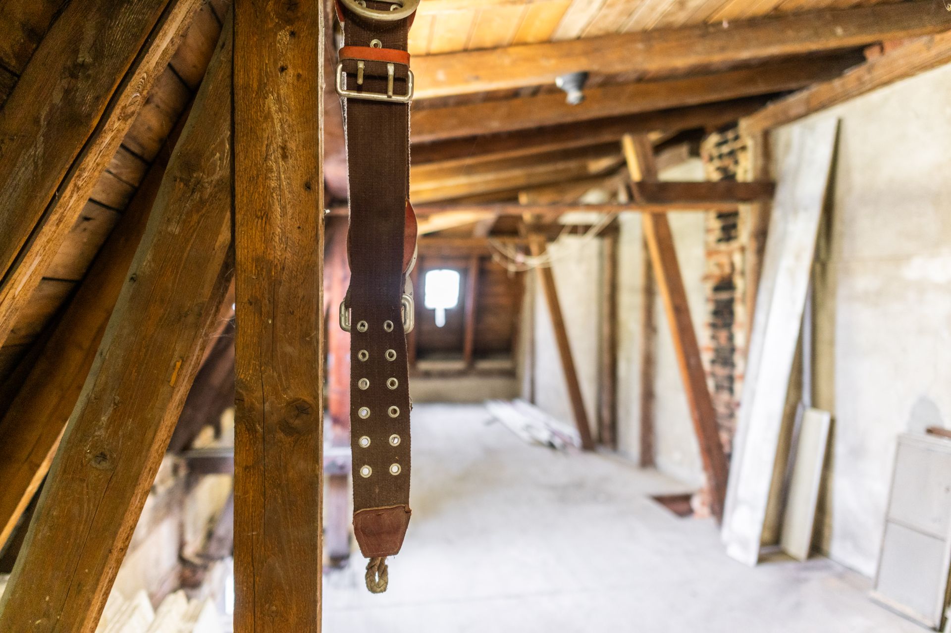 Dachboden mit Holzbalken und einem braunen Ledergurt im Vordergrund.