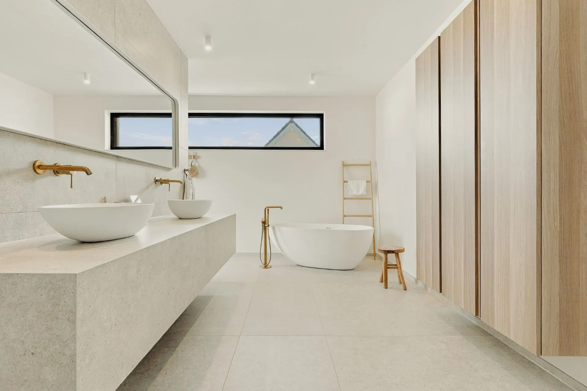 Modernes Badezimmer mit freistehender Badewanne, Doppelwaschbecken und Holzschränken.